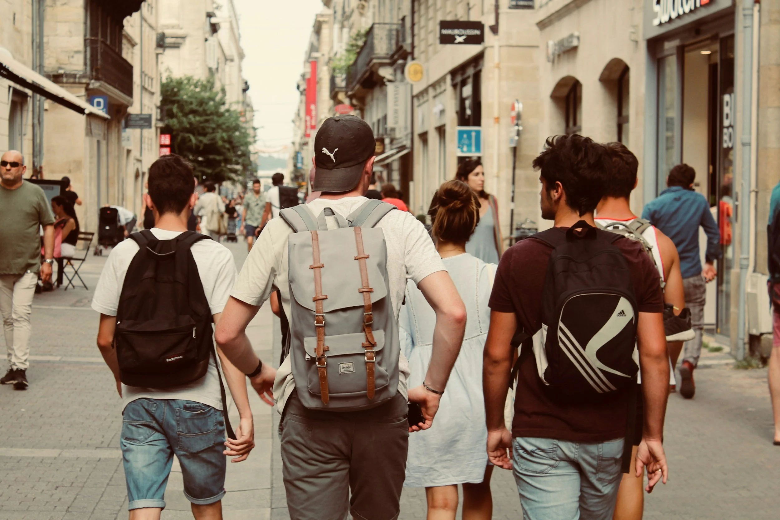 People walking down a busy pedestrian street with shops and stores on either side.