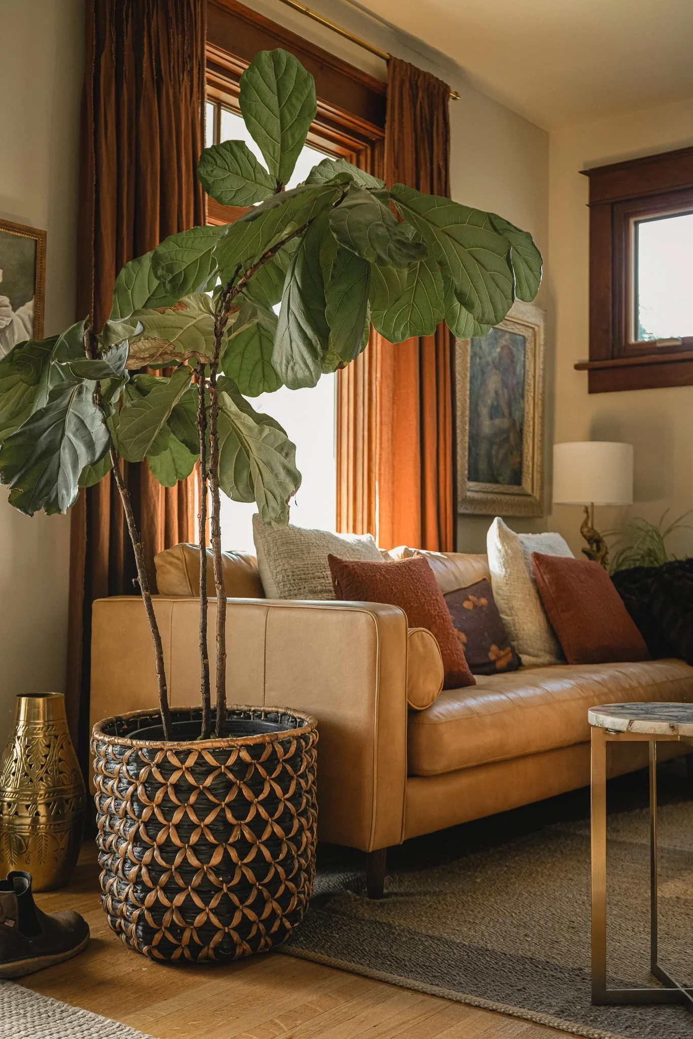 Curated Style Collective-designed living room featuring a cognac leather sofa, fiddle-leaf fig, rust and neutral textiles, vintage artwork and warm wood architectural details.