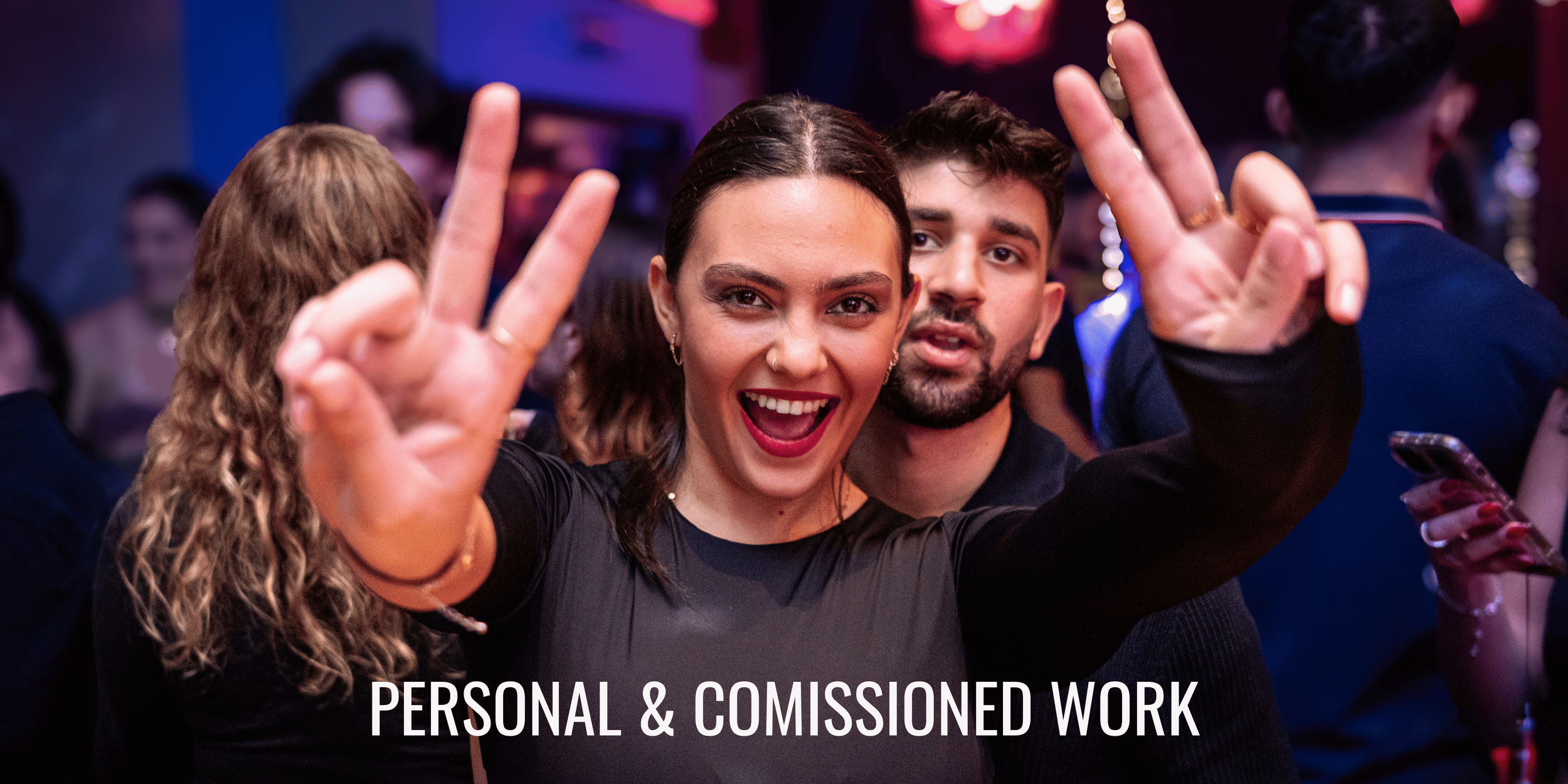 Two smiling young people, a woman and a man, at a social event or party, making peace signs with their hands. The woman is in the foreground, wearing a black top, with dark hair, bright lipstick, and earrings. The man is slightly behind her, with dark hair, facial hair, and a dark shirt. The background shows other people and colorful lights. The text on the image reads "PERSONAL & COMISSIONED WORK."
