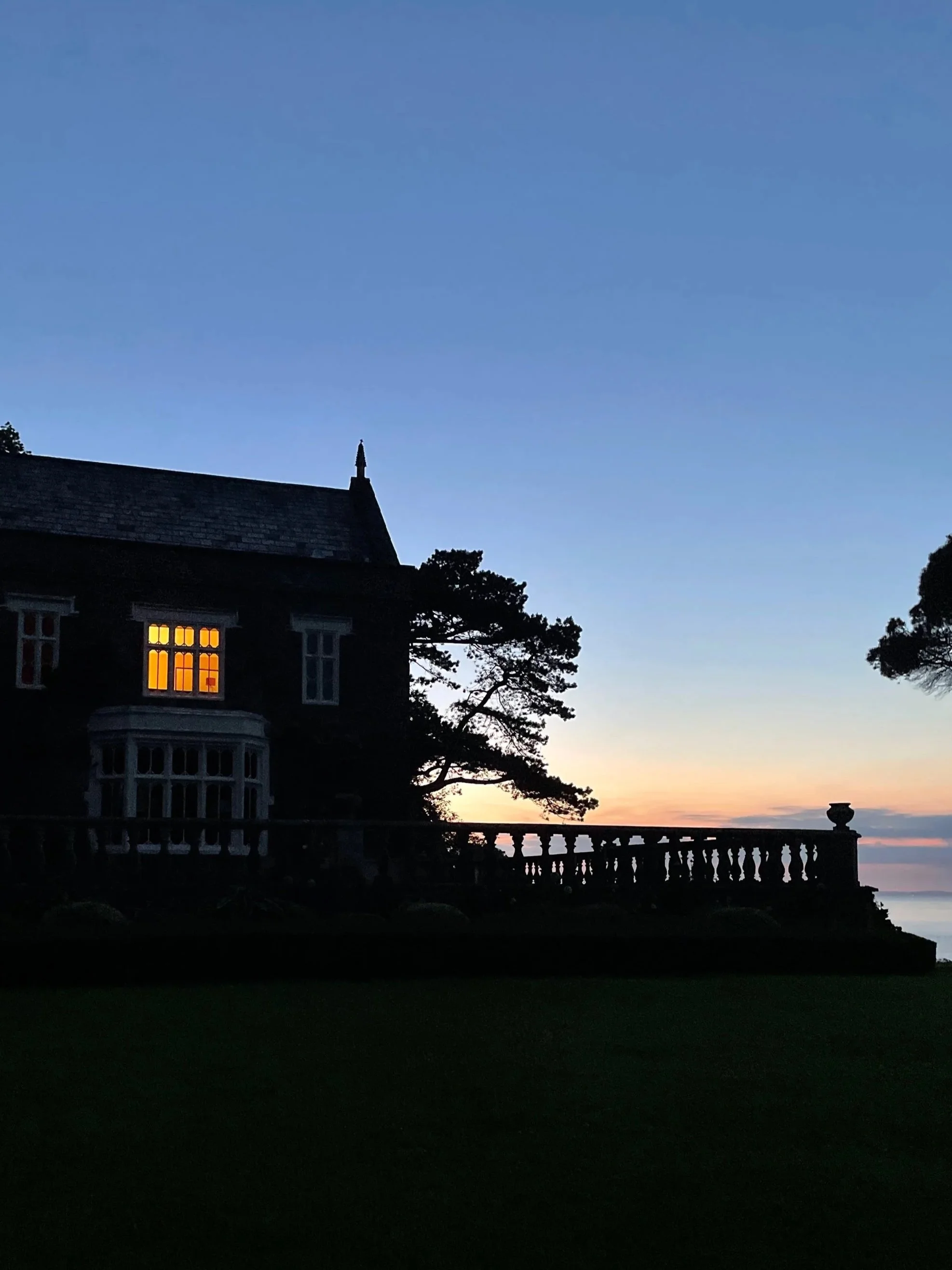 Nighttime scene with a bright full moon in the sky, surrounded by dark clouds, and the silhouette of leafless trees in the foreground.