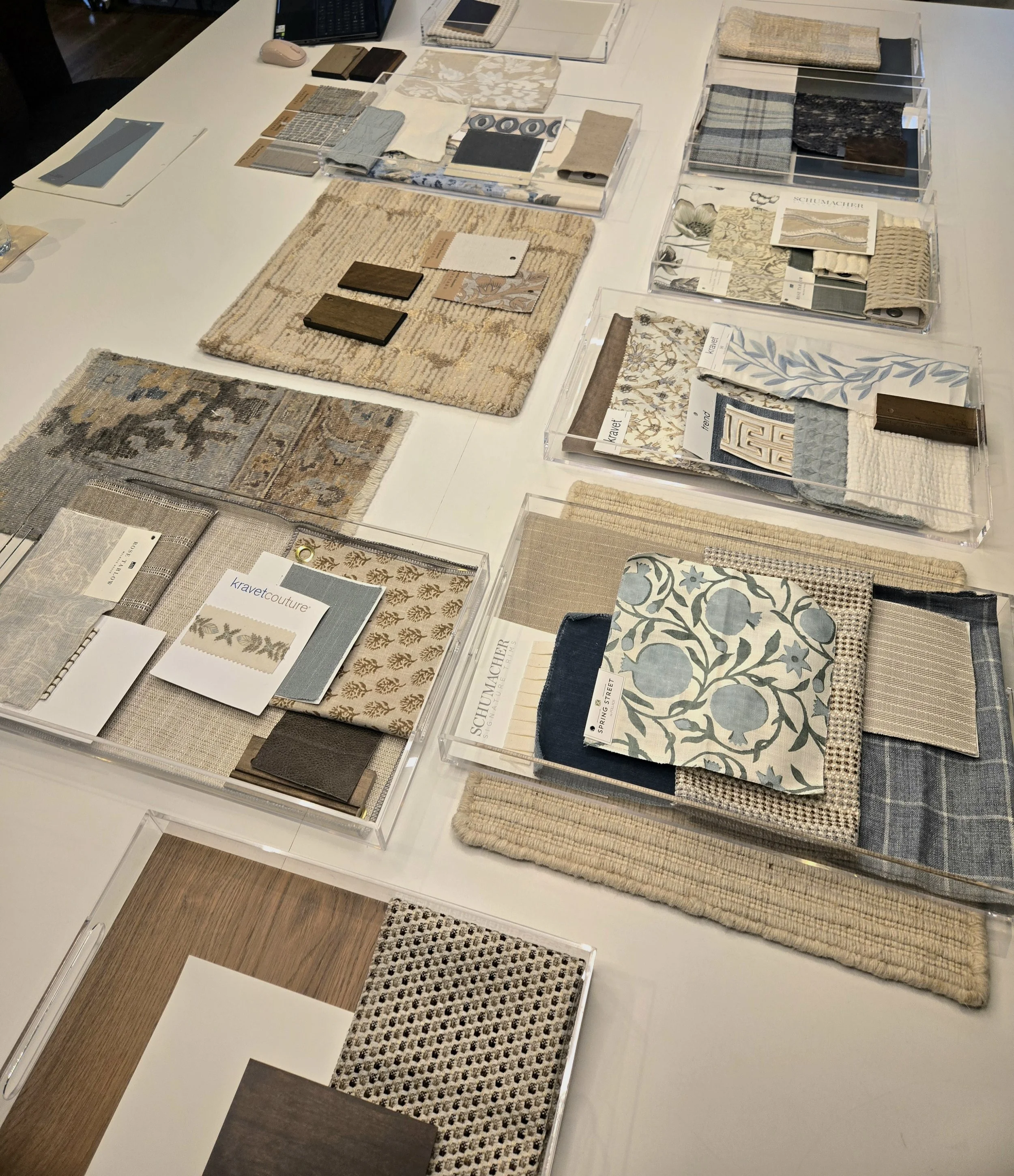 A display of fabric swatches, wallpaper samples, and design materials arranged on a white table for interior decorating or renovation planning.