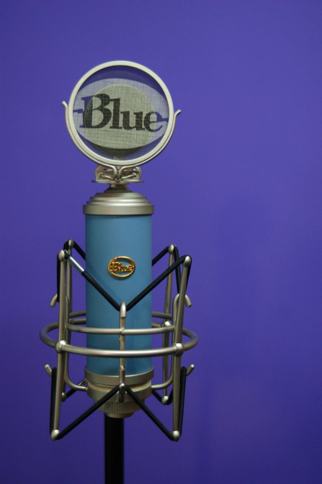 Blue microphone with a round element on top that has the word "Blue" inside a circular frame, set against a purple background.