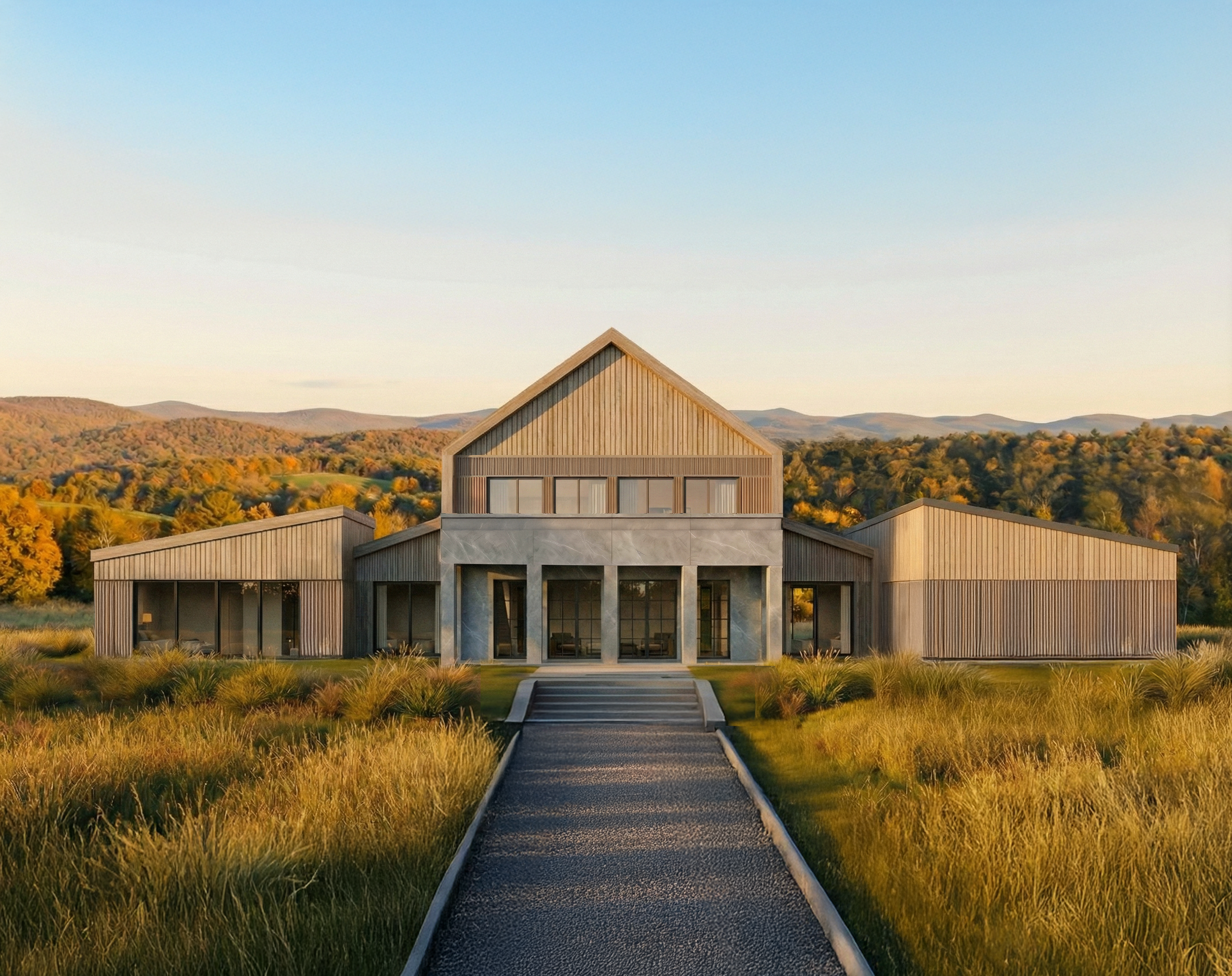 Modern house with a wood and concrete facade, surrounded by grassy fields and trees, with mountains in the background, under a clear sky.