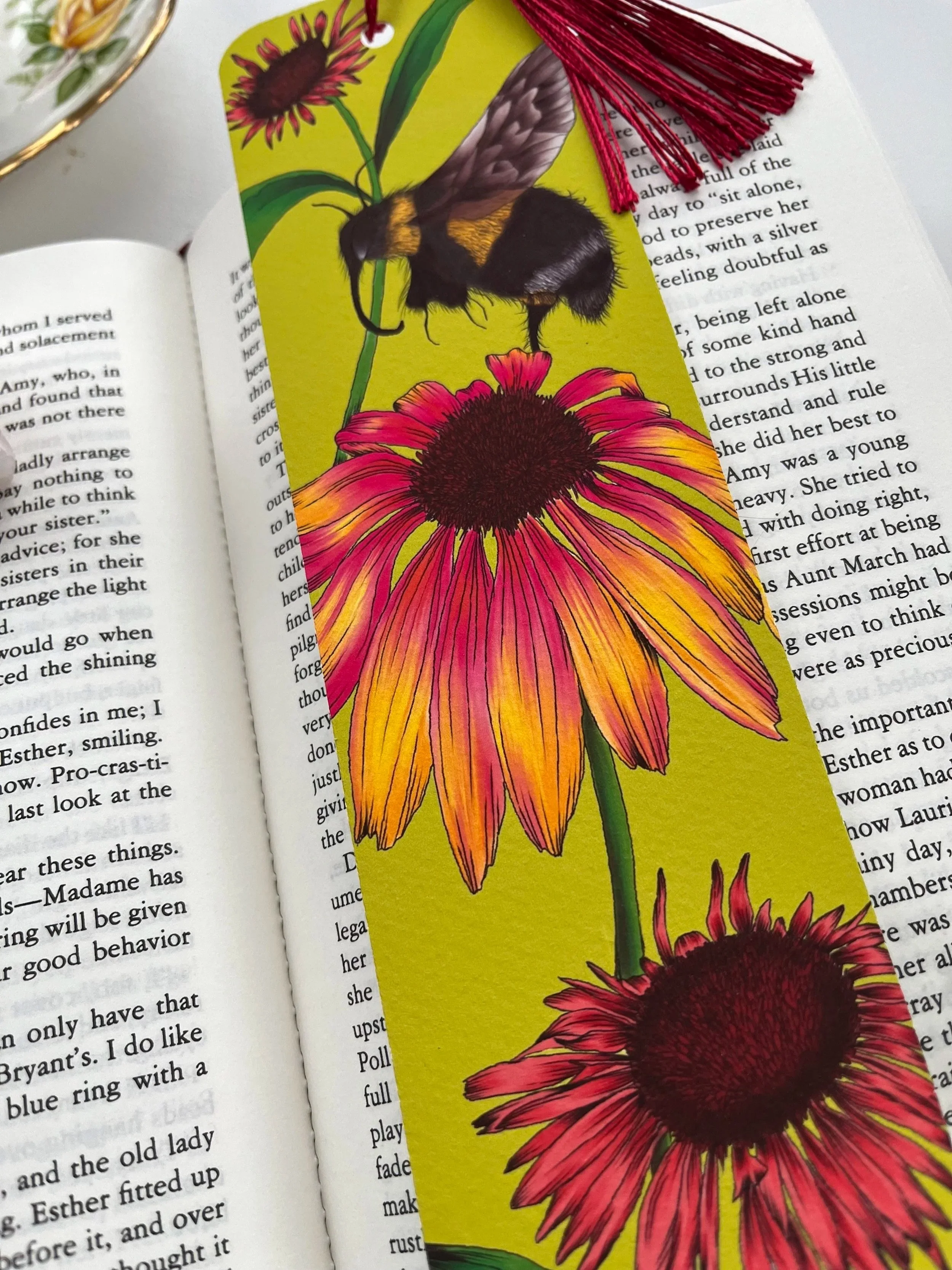 A lime green bookmark with red tassel. The photograph is a close of the bookmark on an open book.