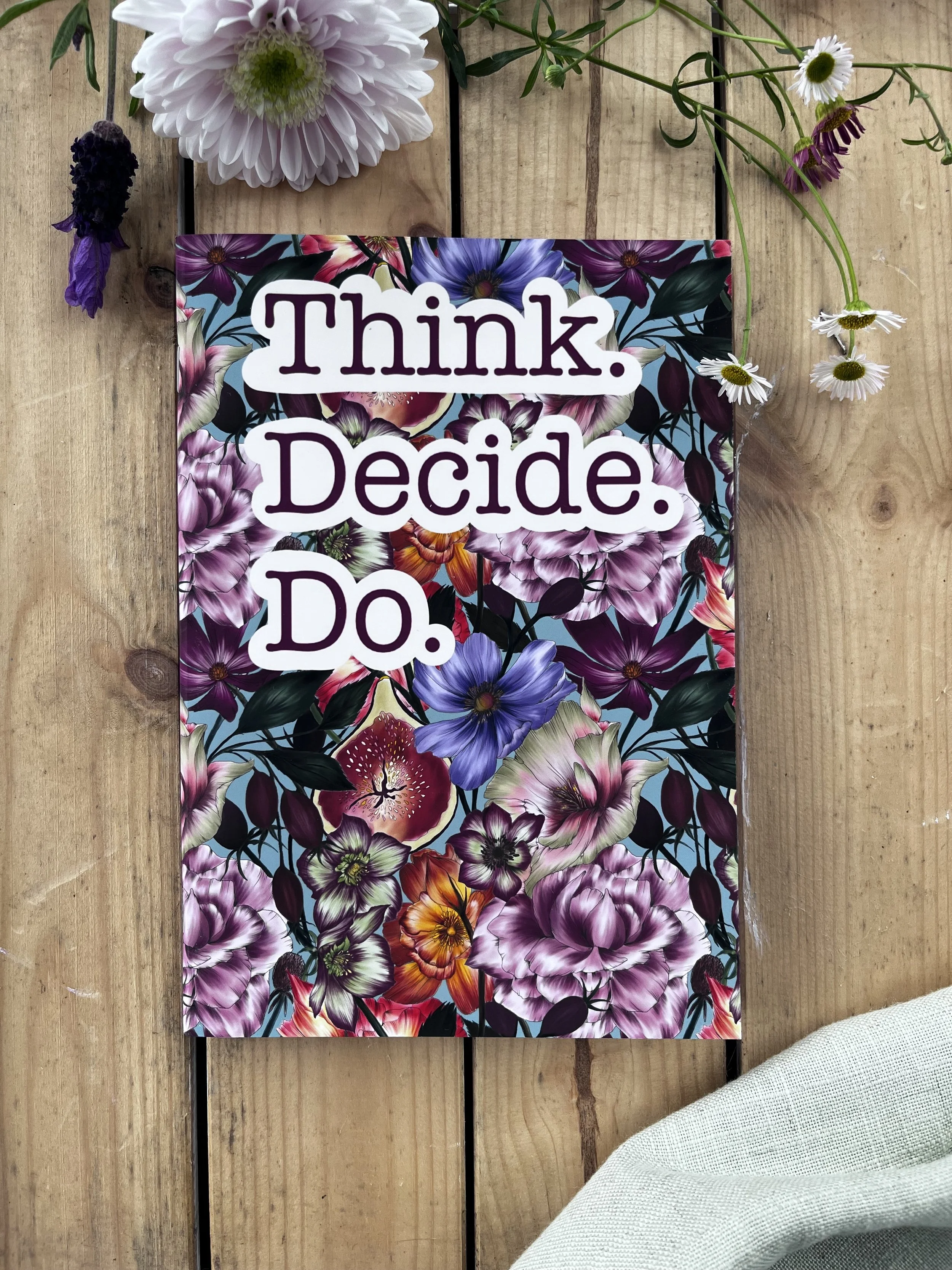Front view of a floral patterned notebook notebook. The slogan on the front of the notebook reads Think, Decide, Do