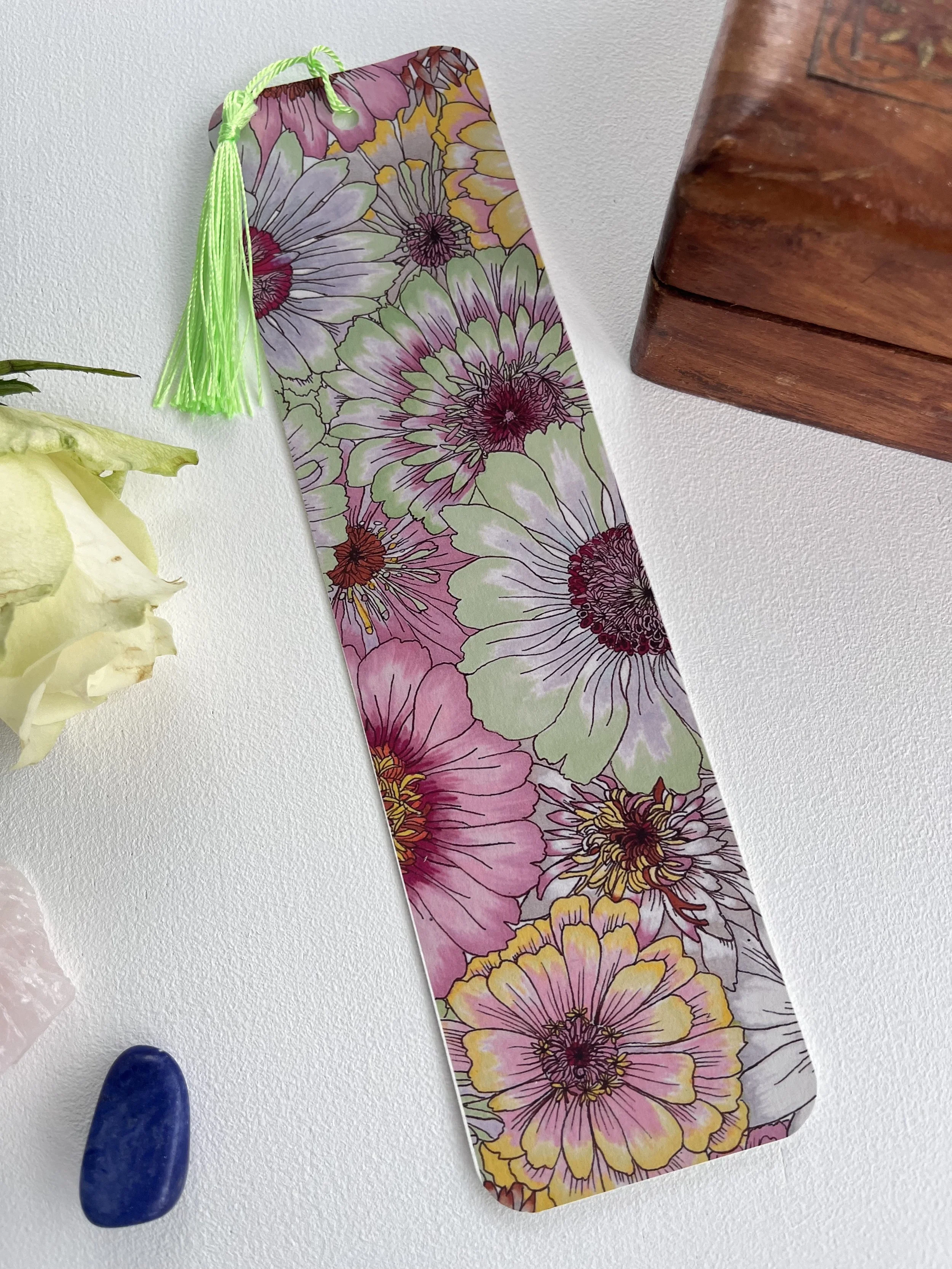 Pastel bookmark with zinnia flowers and tassel. Photographed against a white background.