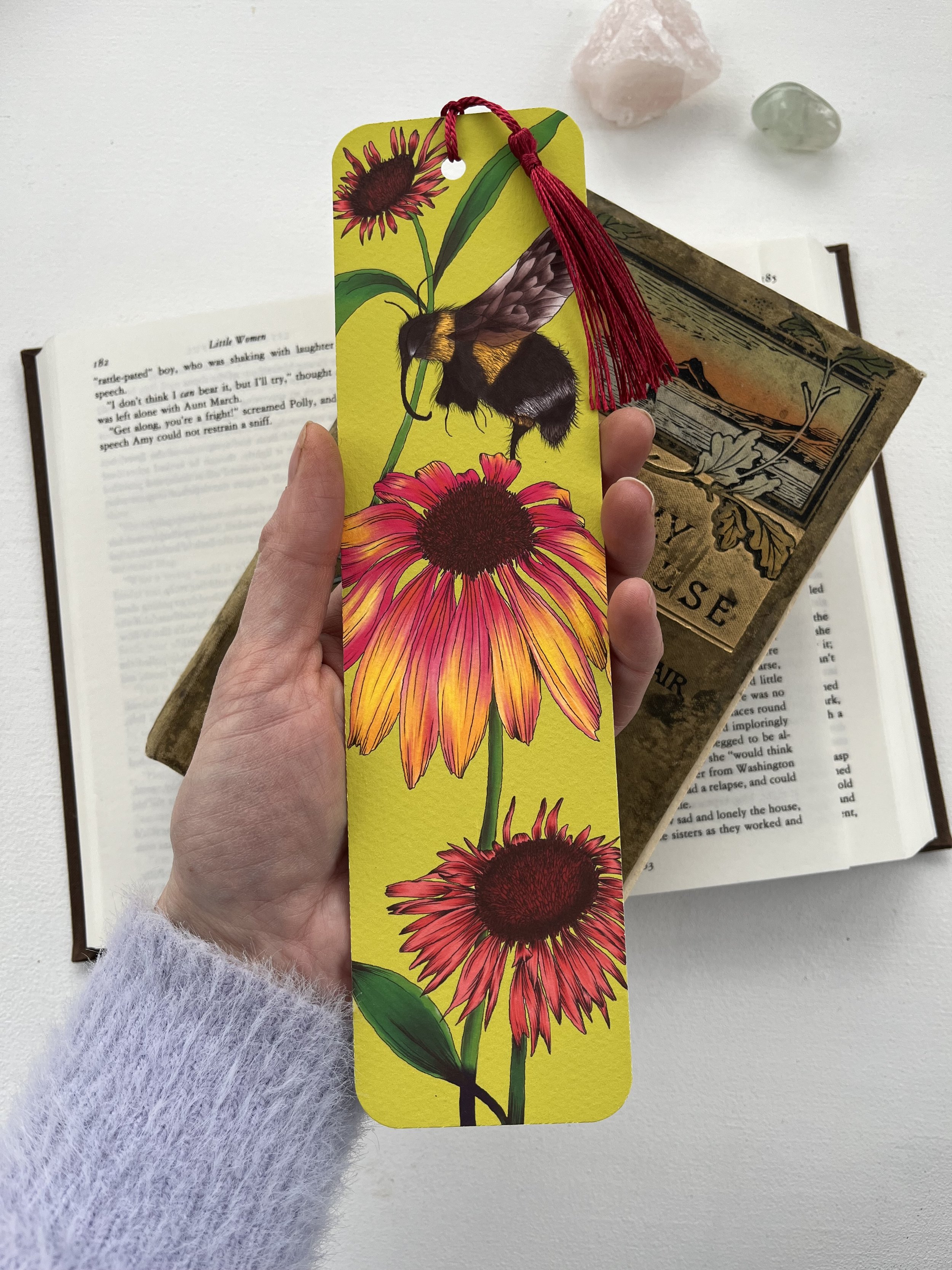 Lime green tassel bookmark with bumblebee design, photographed on an open book