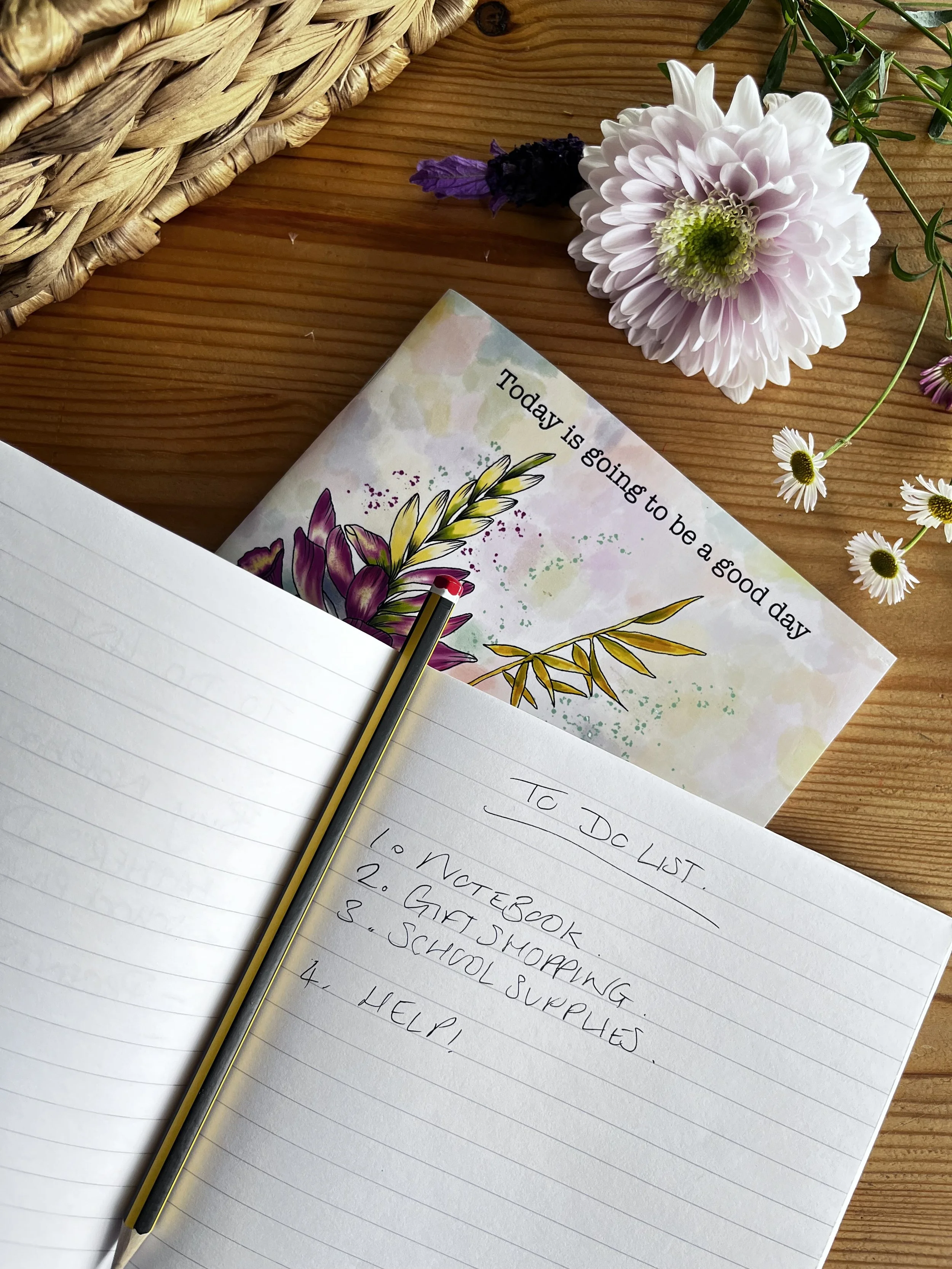 Top of the wildflower notebook showing the slogan ‘today is going to be a good day. An open notebook lays on top of the other with a to do list written on it.