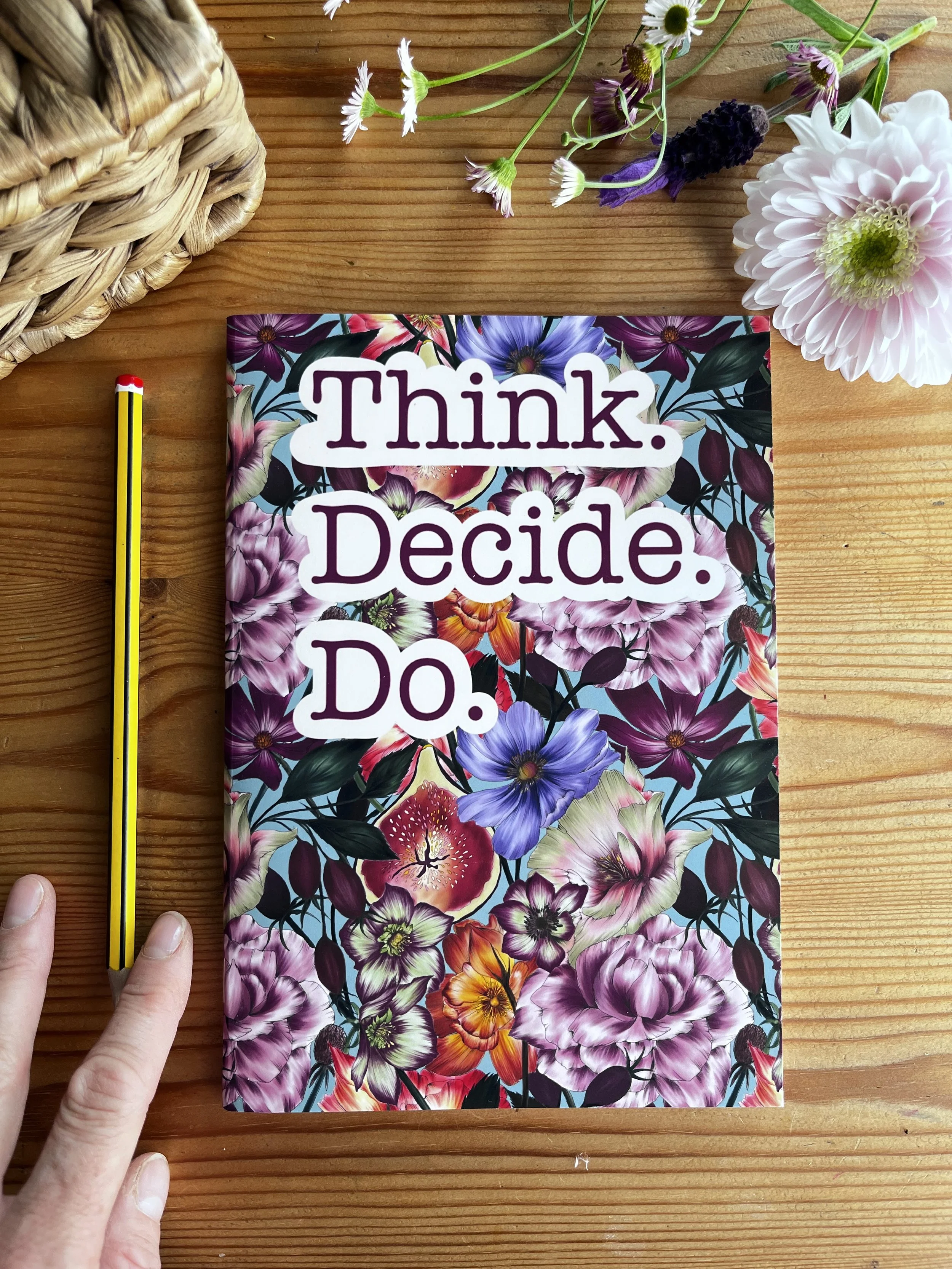 Floral notebook with a pencil on a wooden table. Photographed with flowers