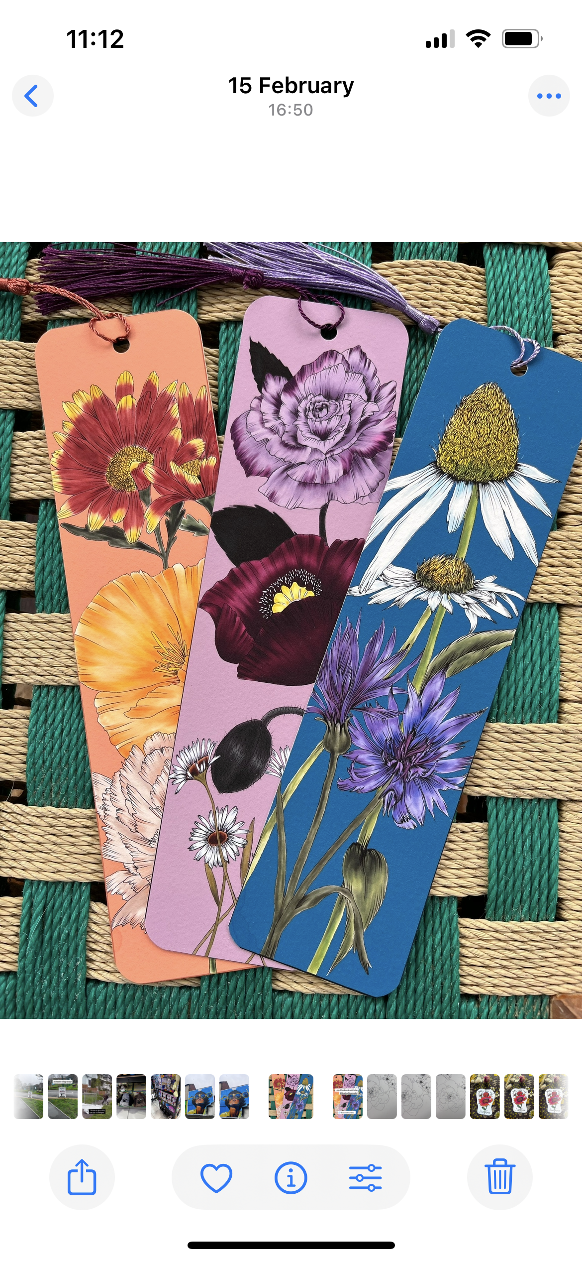Three colorful bookmarks with floral illustrations resting on a woven surface.