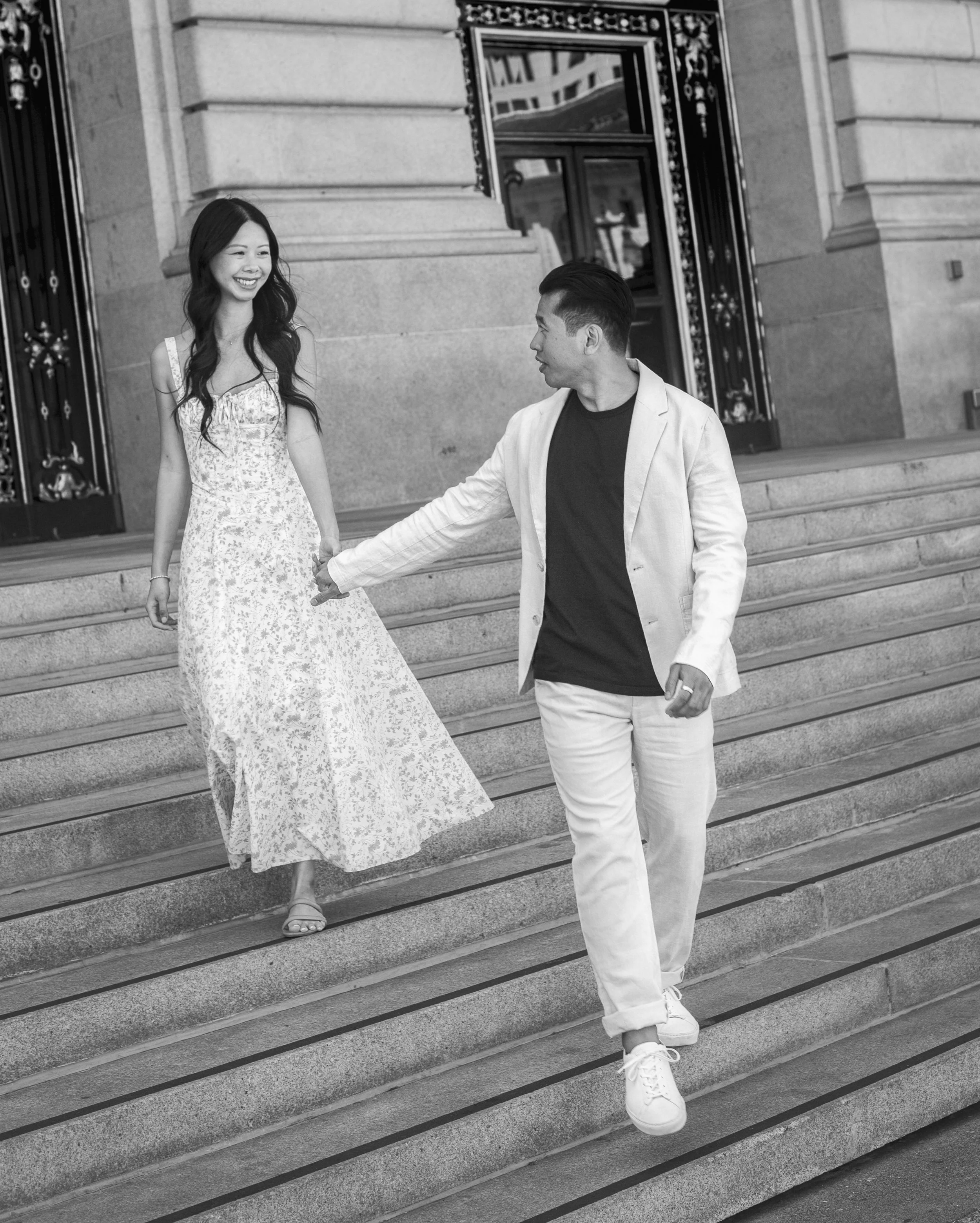 Bride and groom walking down the steps of San Francisco City Hall during their engagement session.