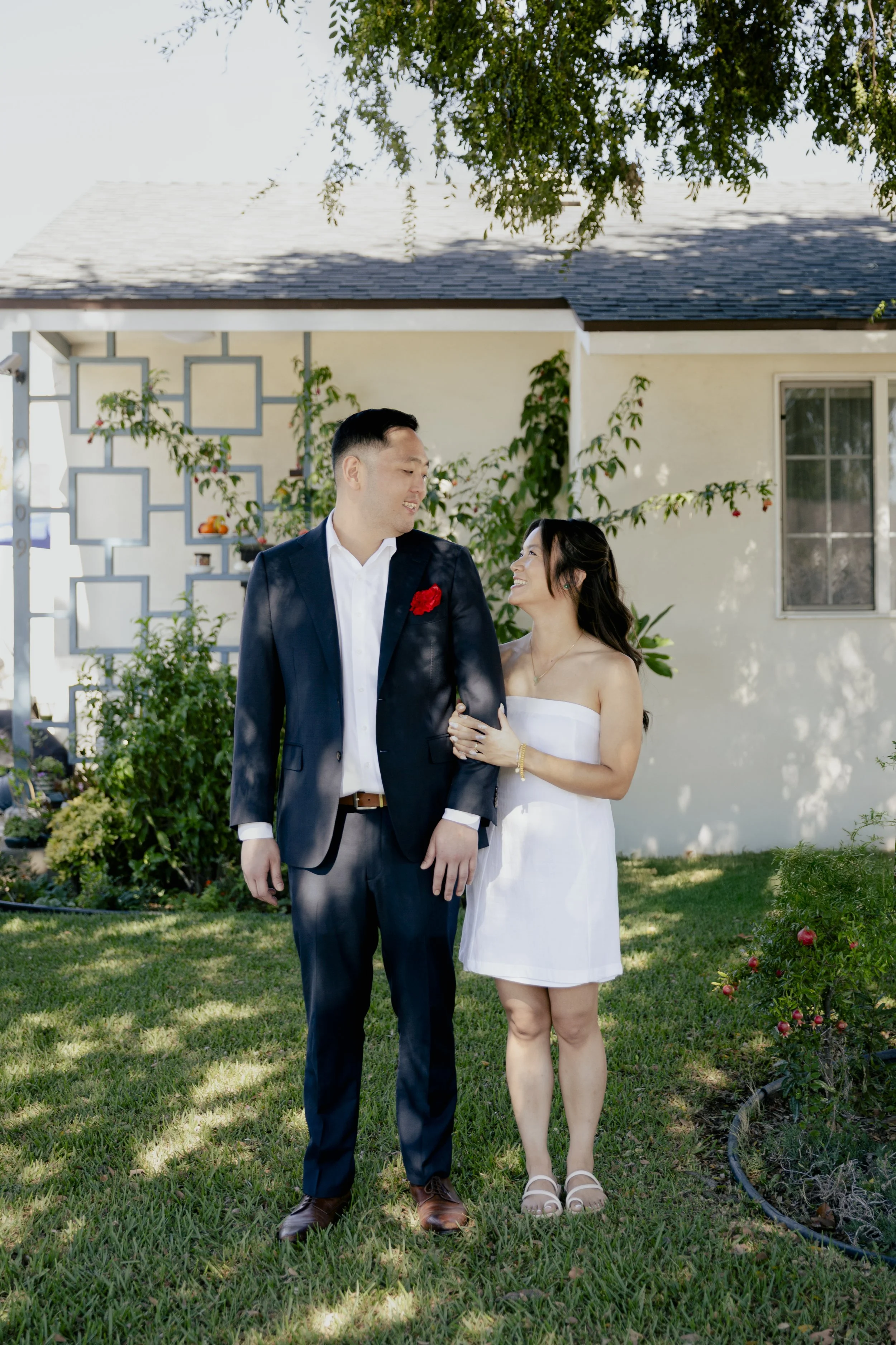 Couple standing together during a tea ceremony portrait with the bride holding the groom’s arms.