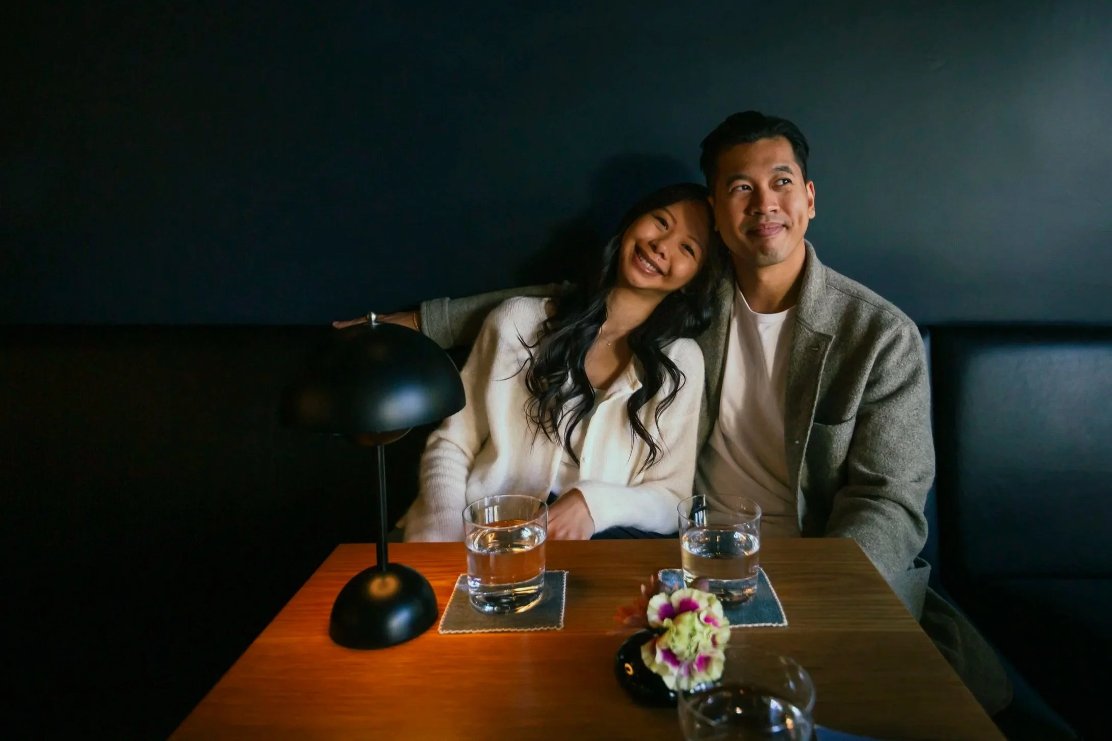 Bride and groom seated closely together in a booth at a bar in San Francisco.