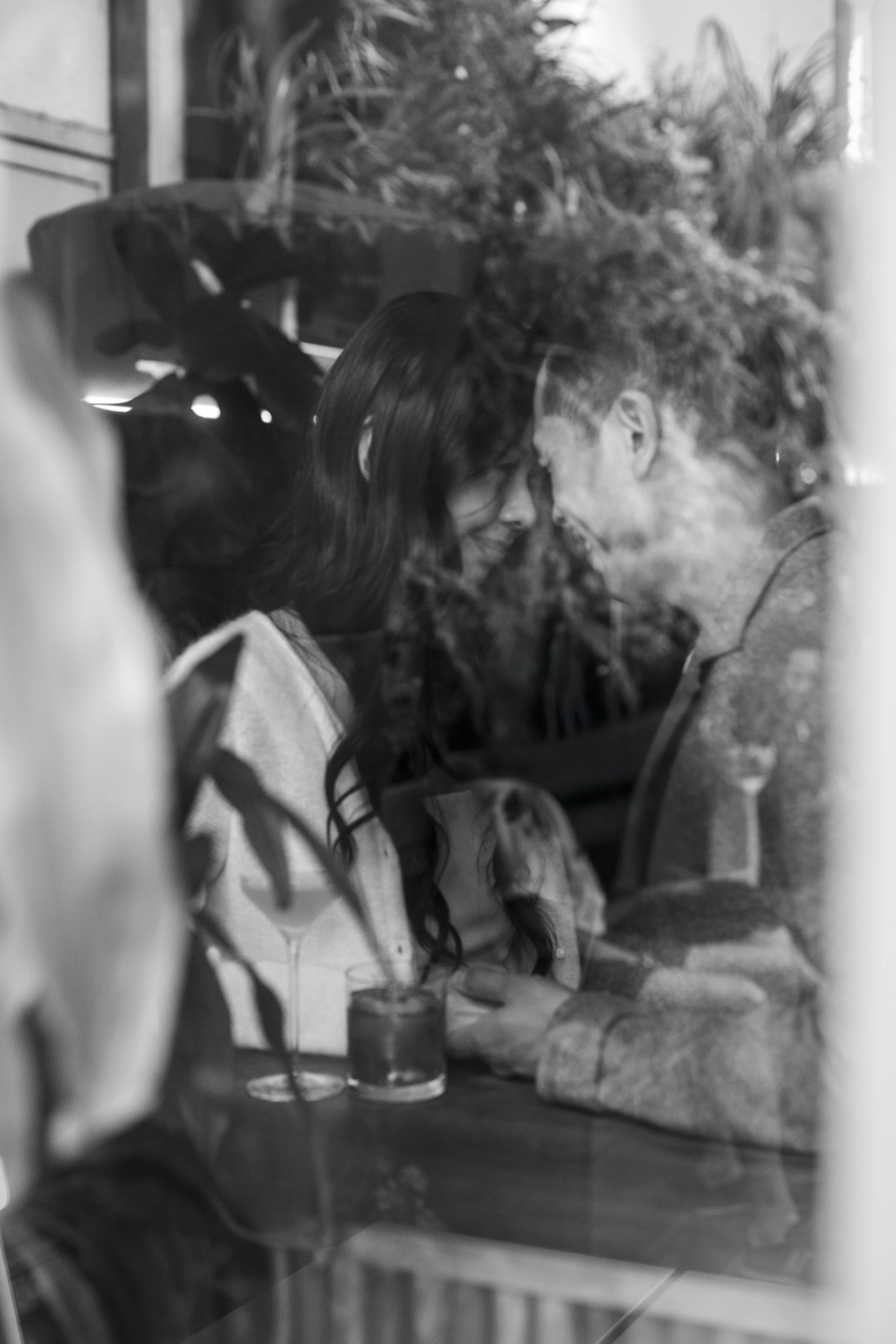 Bride and groom touching foreheads as seen through a bar window during their San Francisco engagement session.