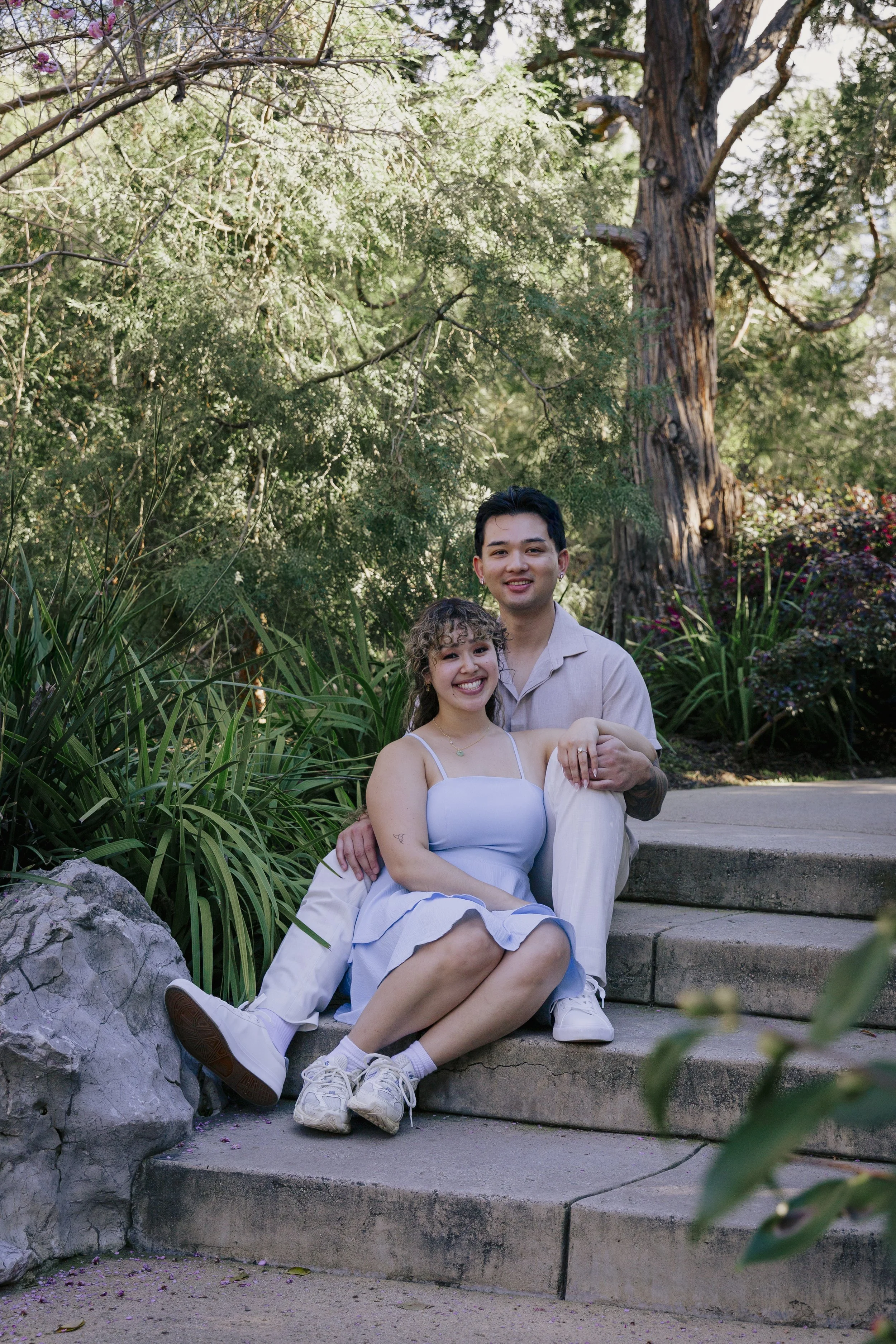 Couple sitting together on small garden steps during their engagement session.