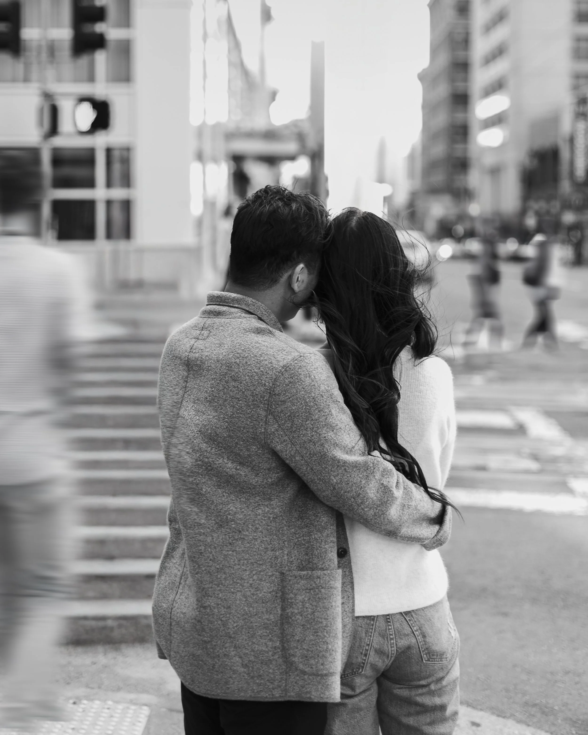 Groom holding the bride at a San Francisco street corner while people move around them in soft blur.