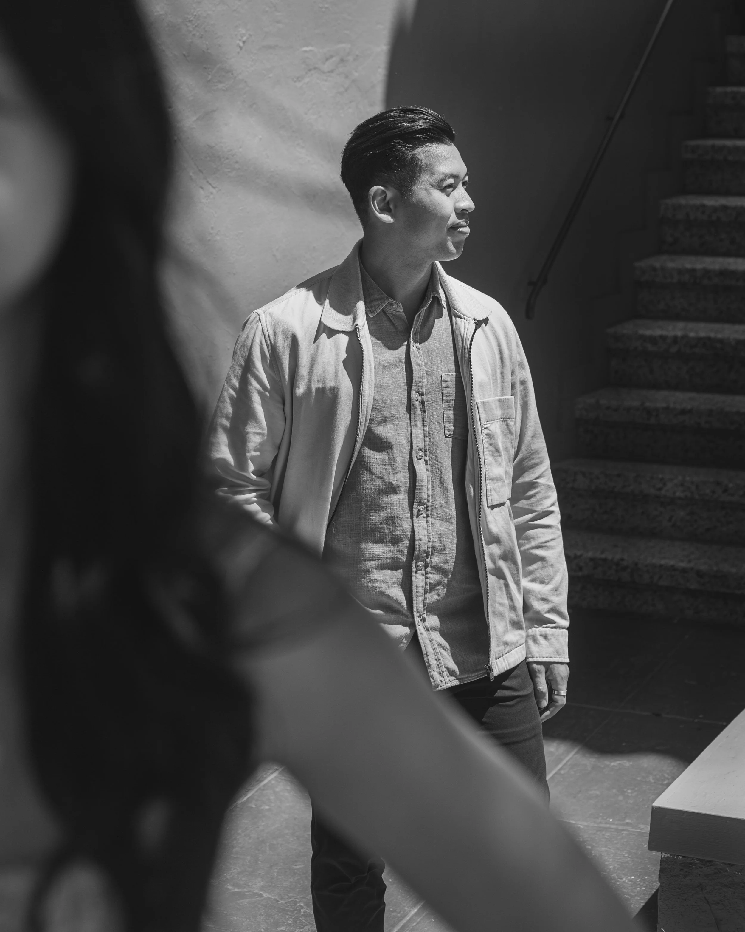 Portrait of the groom looking to the side with the bride blurred softly in the foreground.