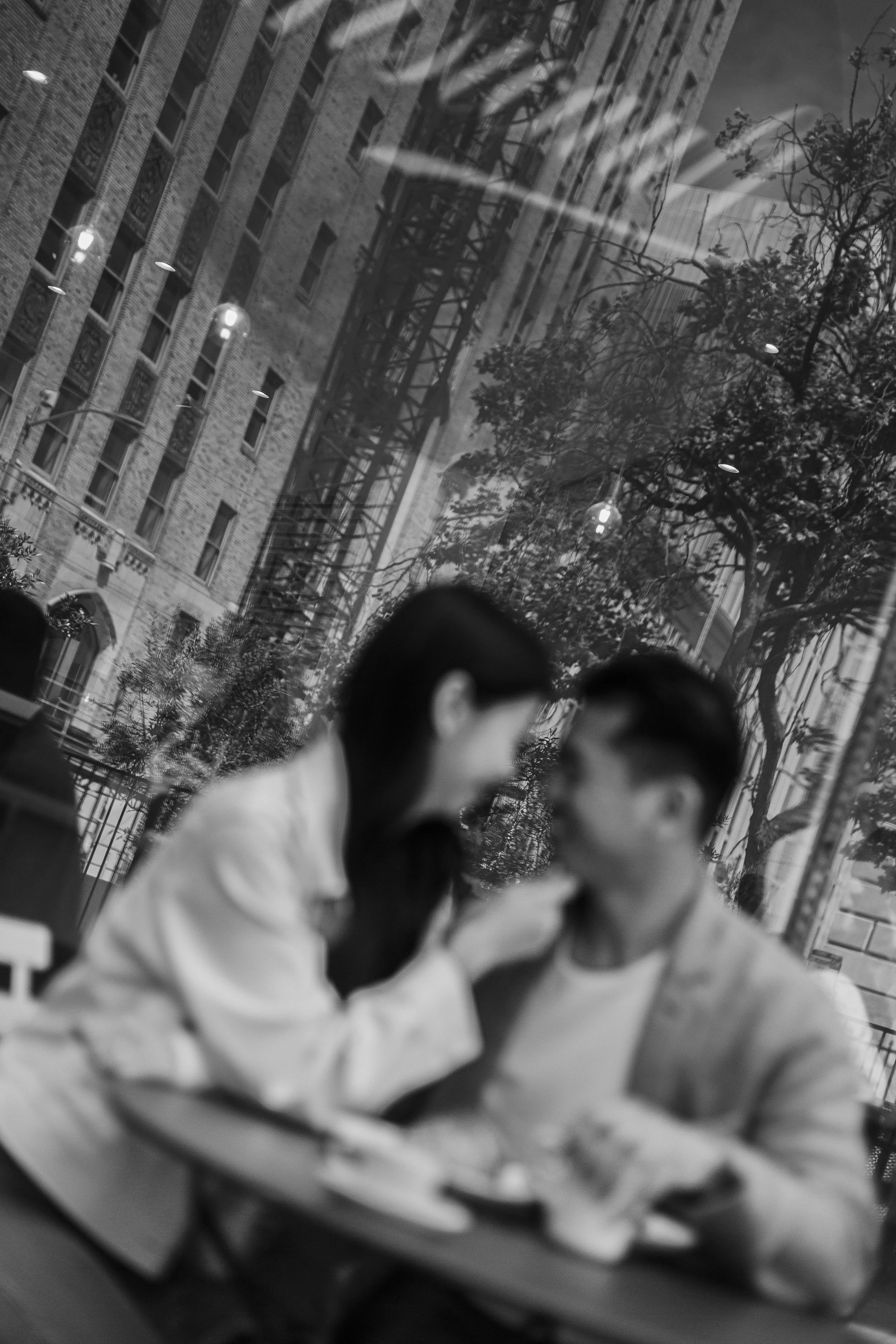 Couple embracing on a patio with city reflections behind them during their engagement session in San Francisco.