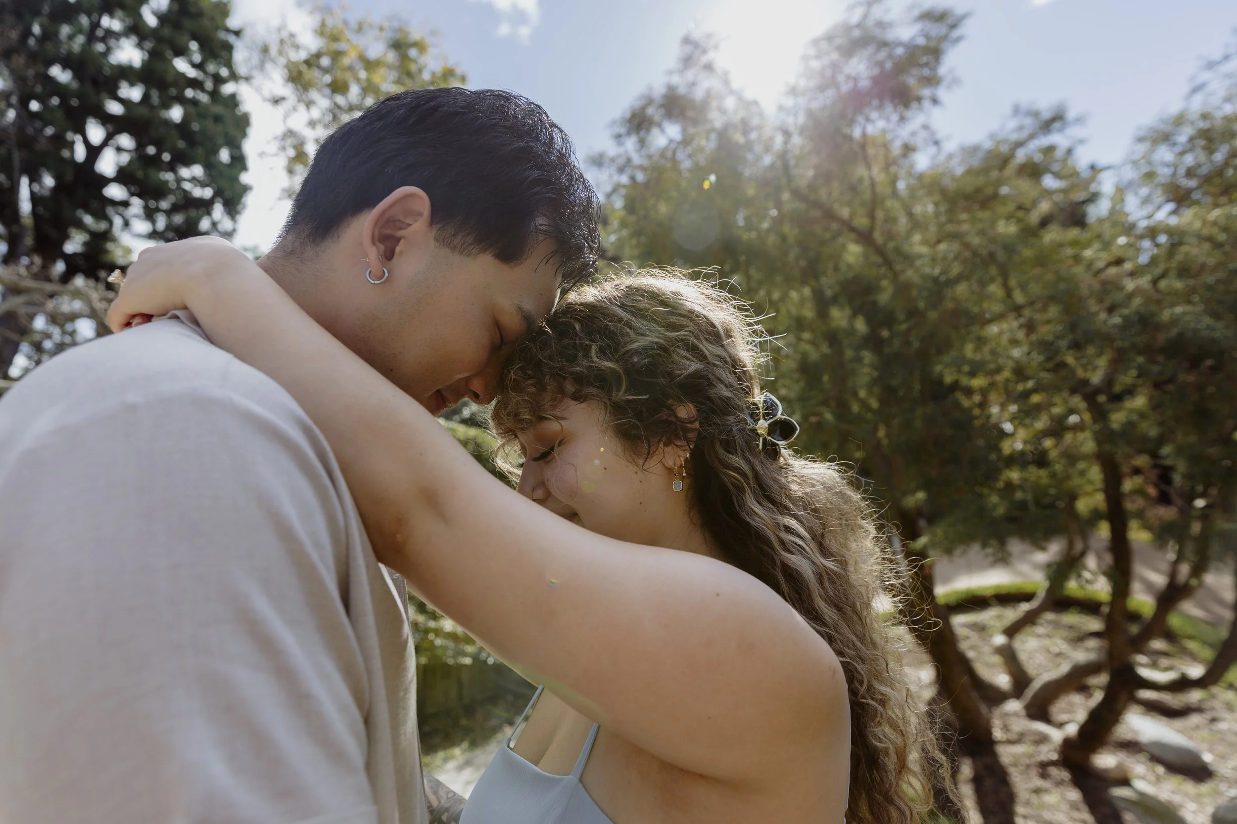 Couple embracing with their foreheads touching in a quiet garden moment.