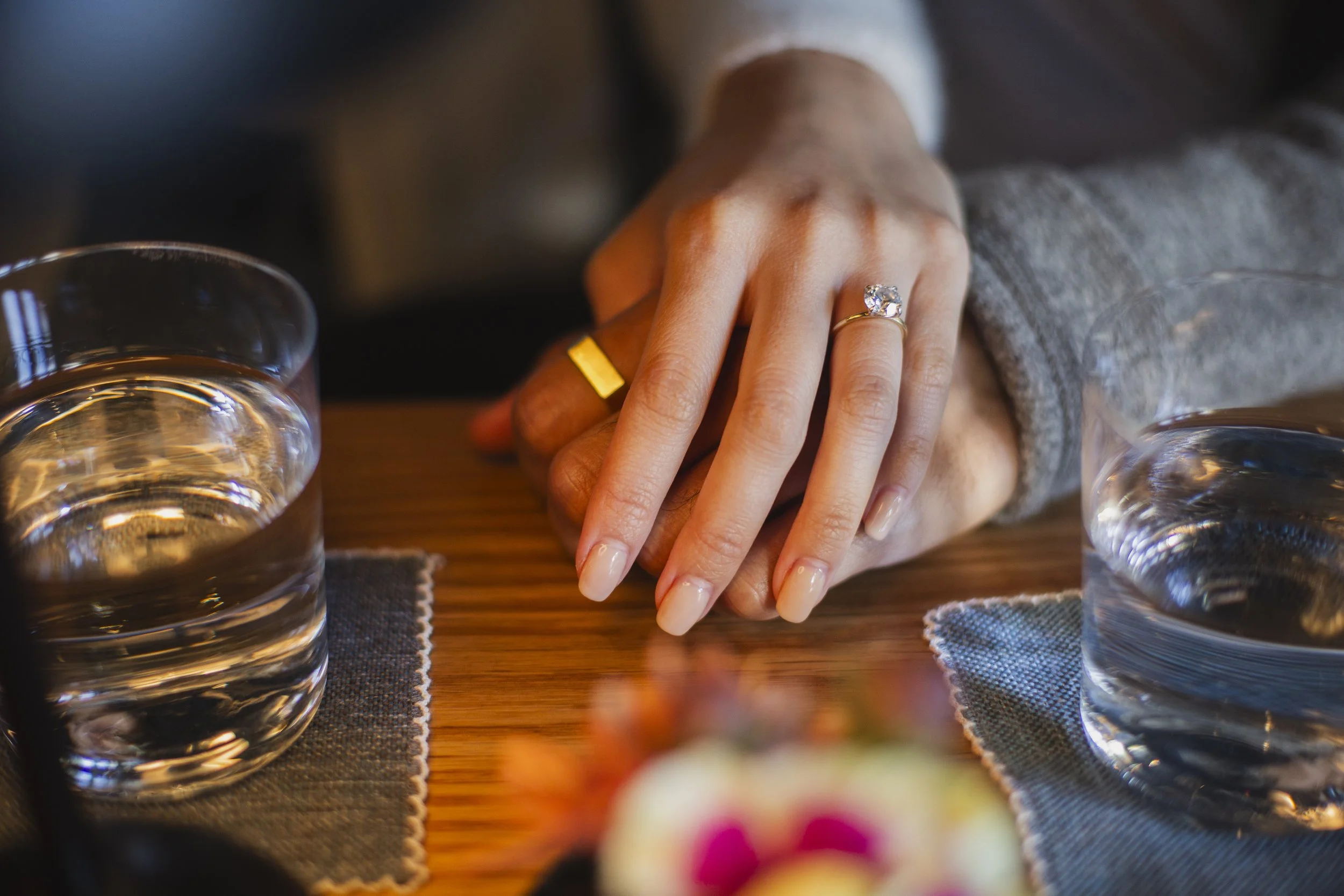 Engagement ring resting on the groom’s hand at a bar table during a San Francisco engagement session.