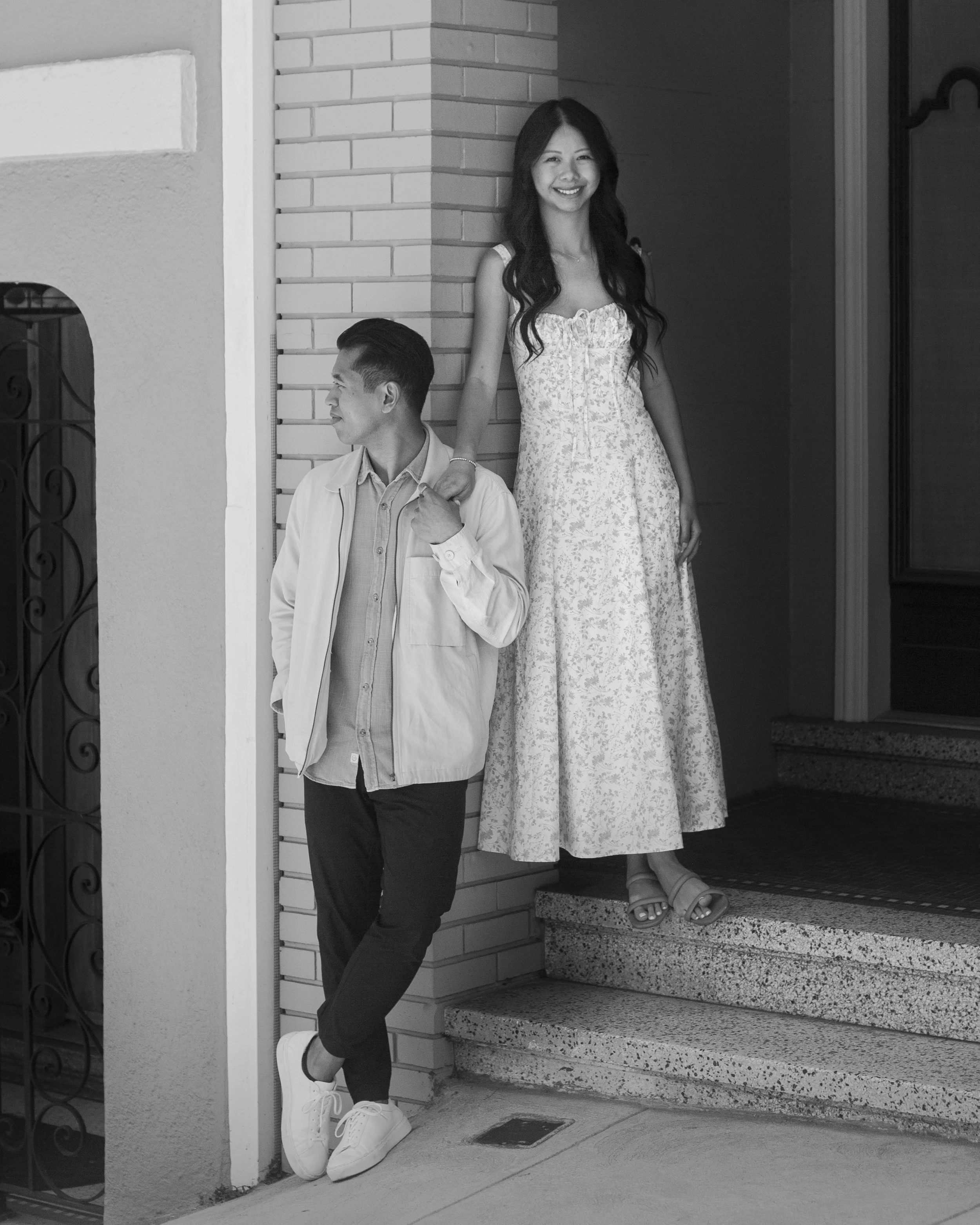 Couple standing in a home entryway with the bride looking toward the camera and her hand resting on the groom’s shoulder.