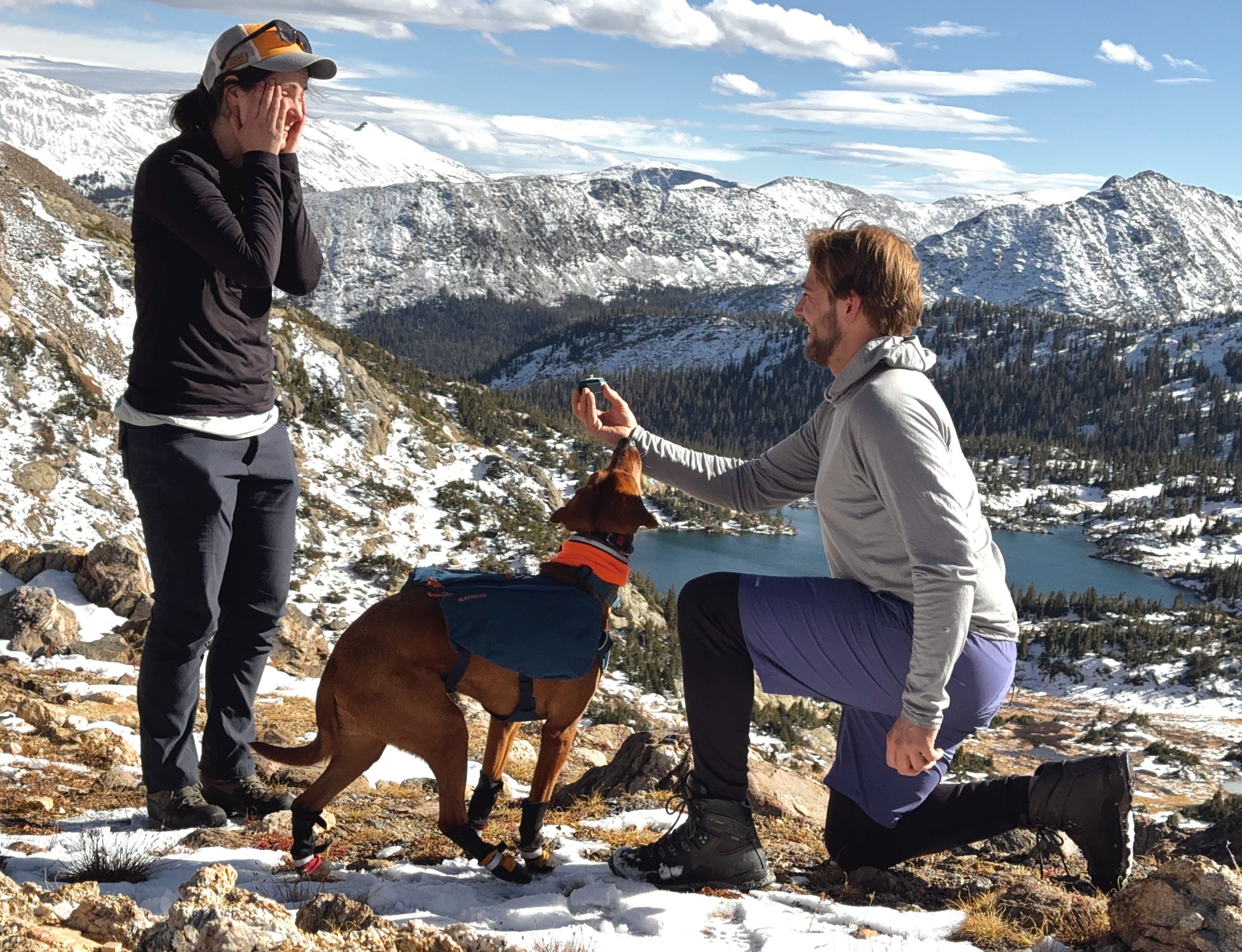 Hunter proposing to Kate in a snowy mountain landscape with peaks and a lake in the background. Penny also says yes.