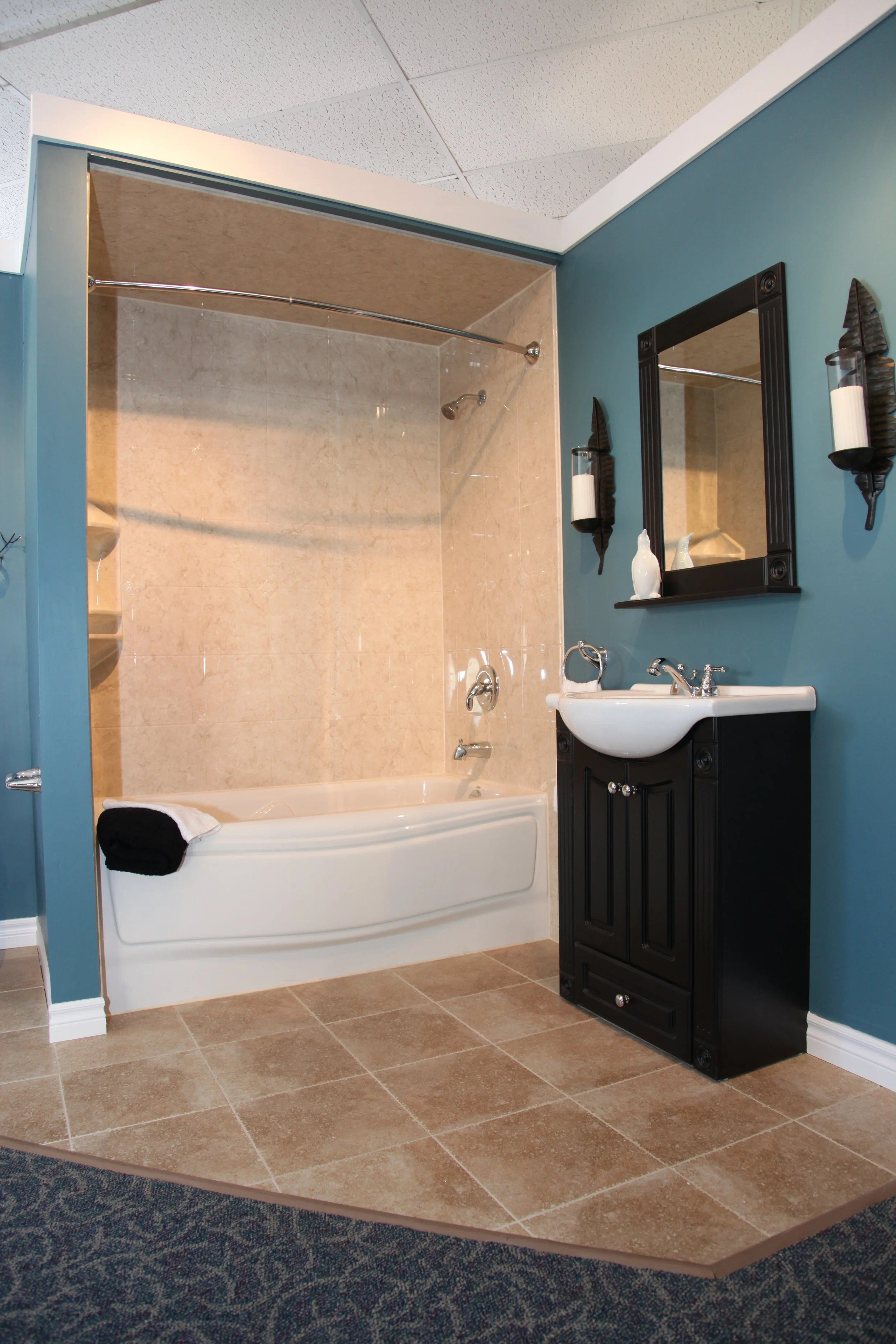 A bathroom with a bathtub, shower, black vanity with a sink, mirror, and wall-mounted candles.