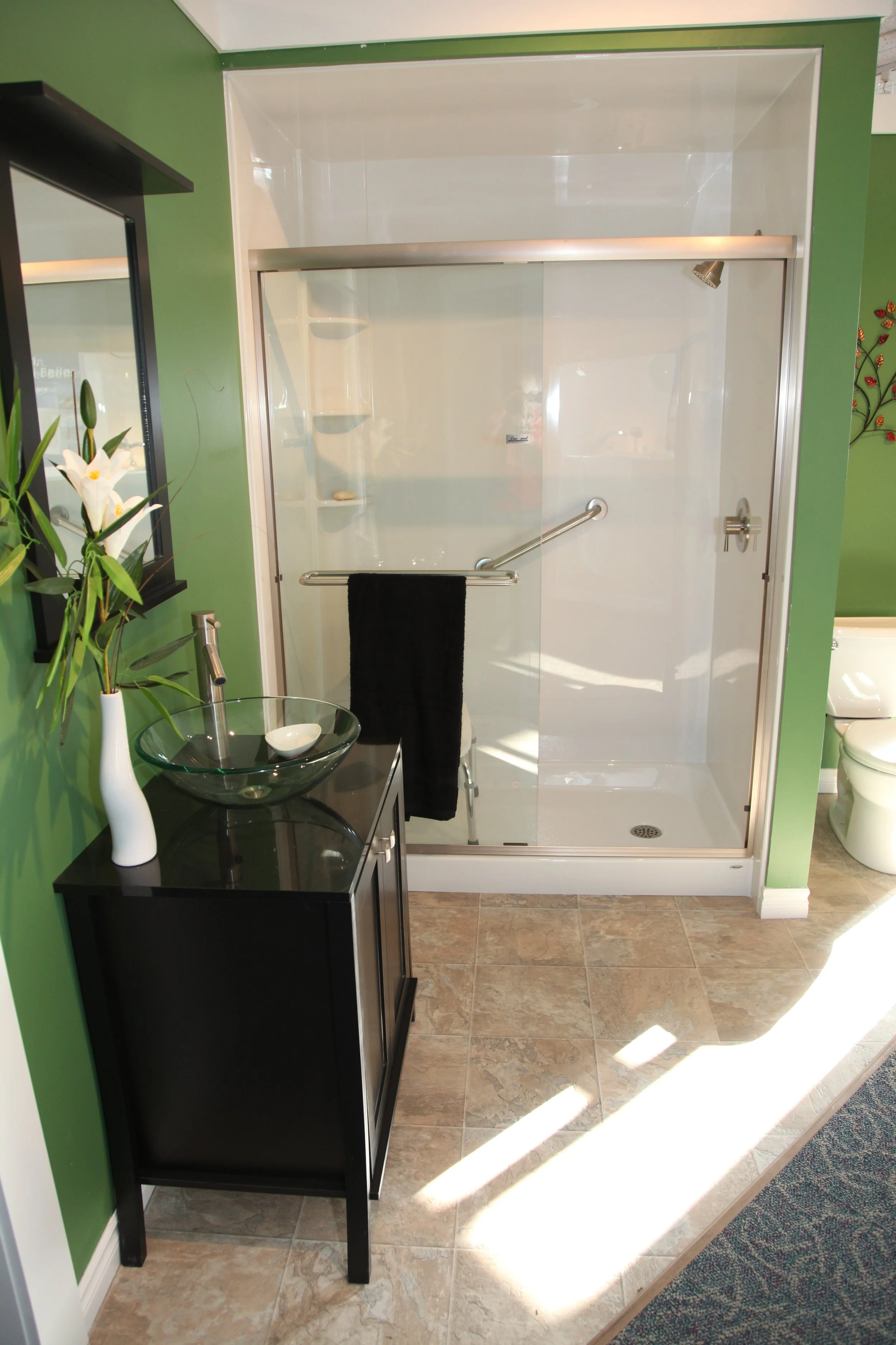 Bathroom with a walk-in shower, black vanity with a vessel sink, and a decorative plant in a white vase.