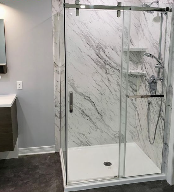 Modern glass shower enclosure with marble walls and shower fixtures