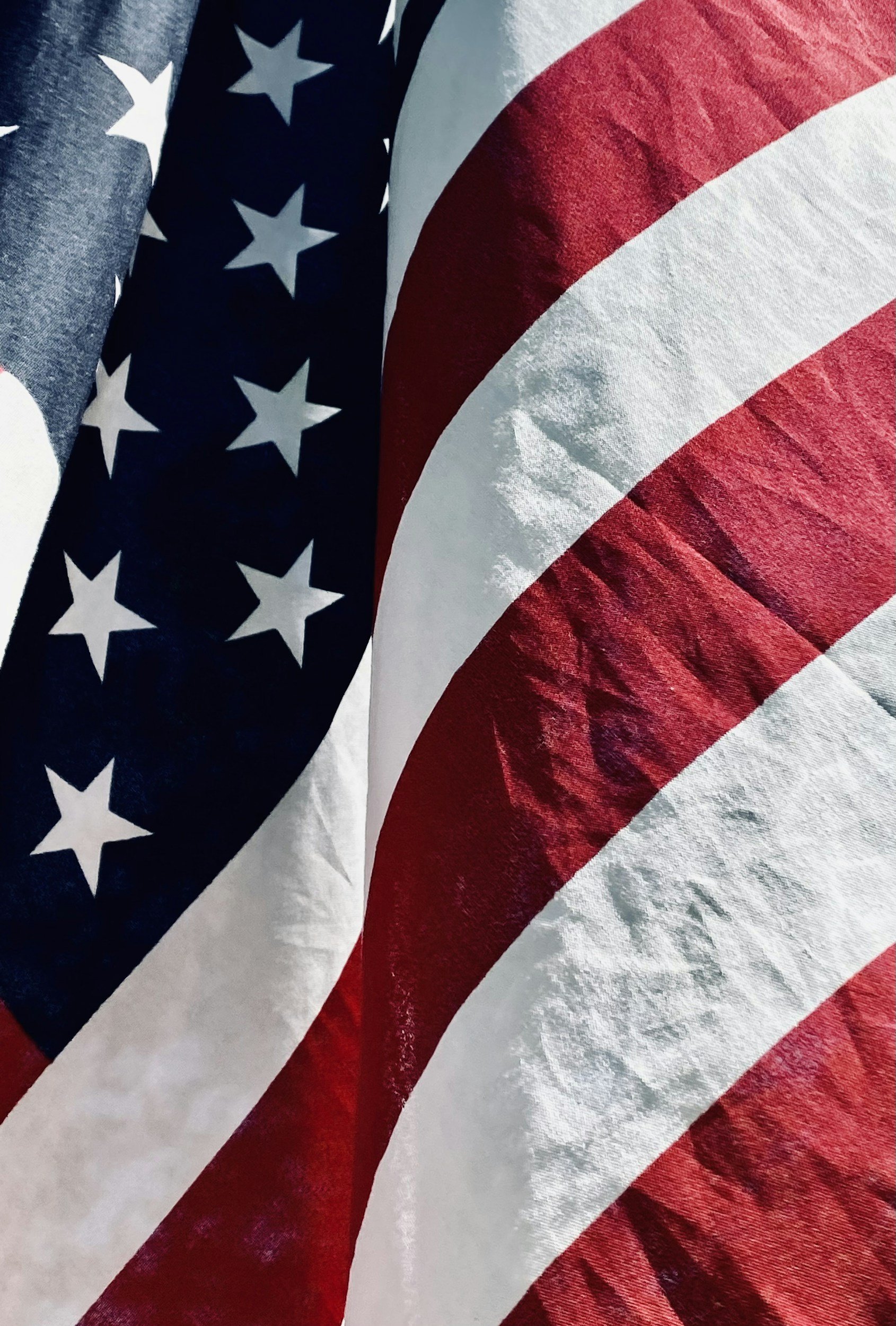 Close-up of an American flag with red and white stripes and a blue canton with white stars.