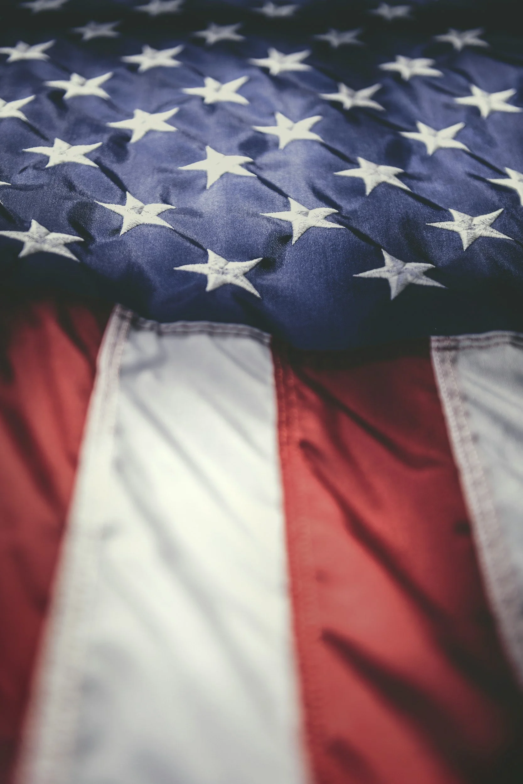 Close-up of a folded American flag with visible white stars on blue background and red and white stripes.