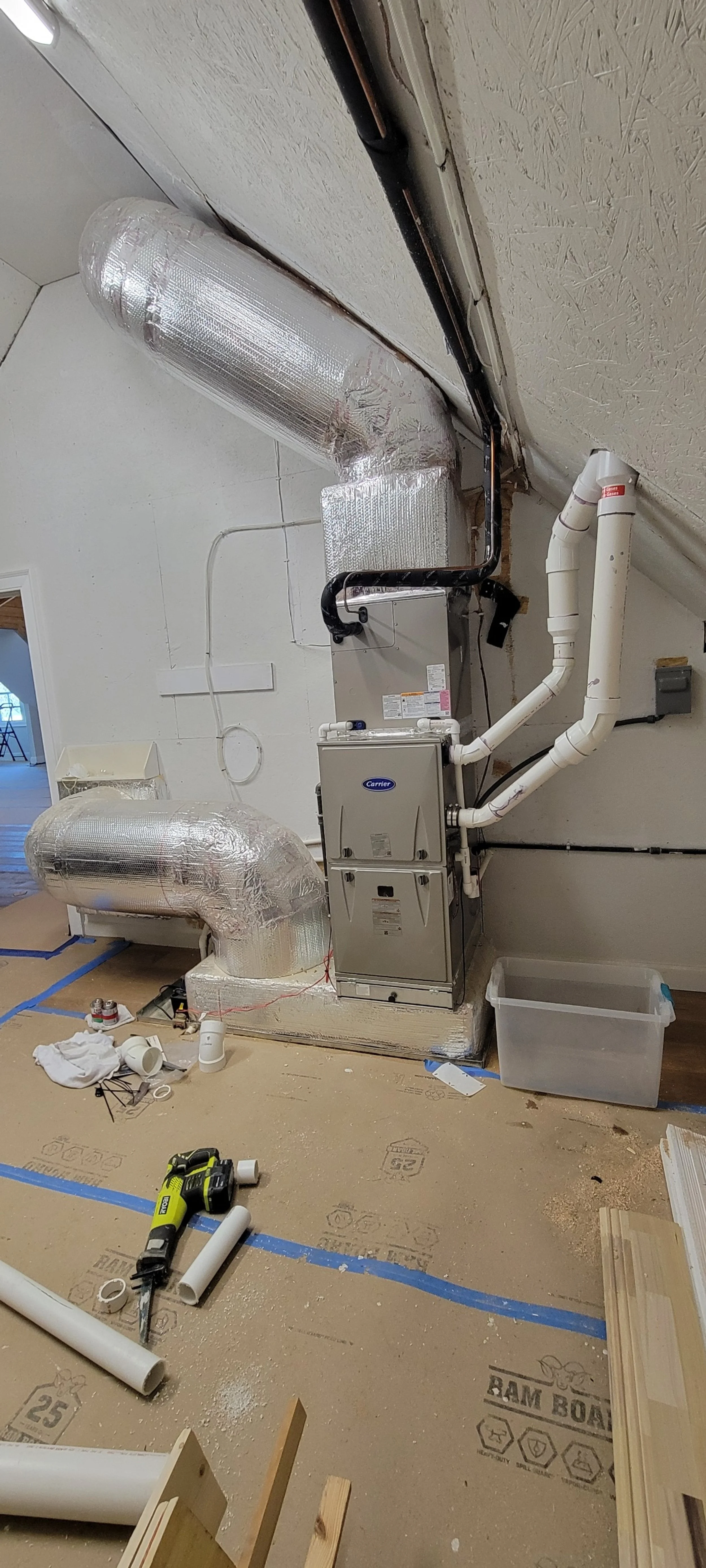 Unfinished basement with HVAC system and ductwork, construction tools, and materials scattered on the floor.