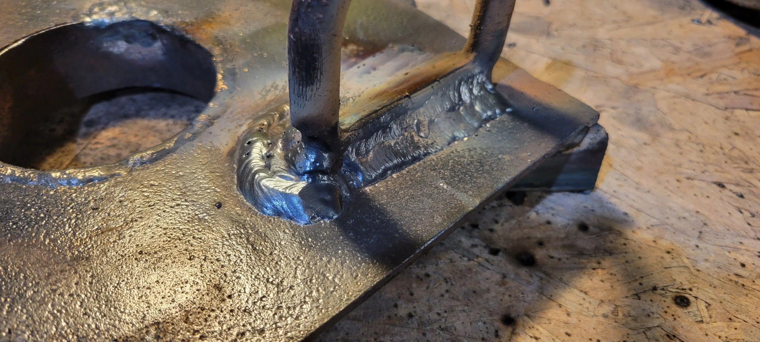 Close-up of a metal sculpture with welded joints on a wooden workbench.