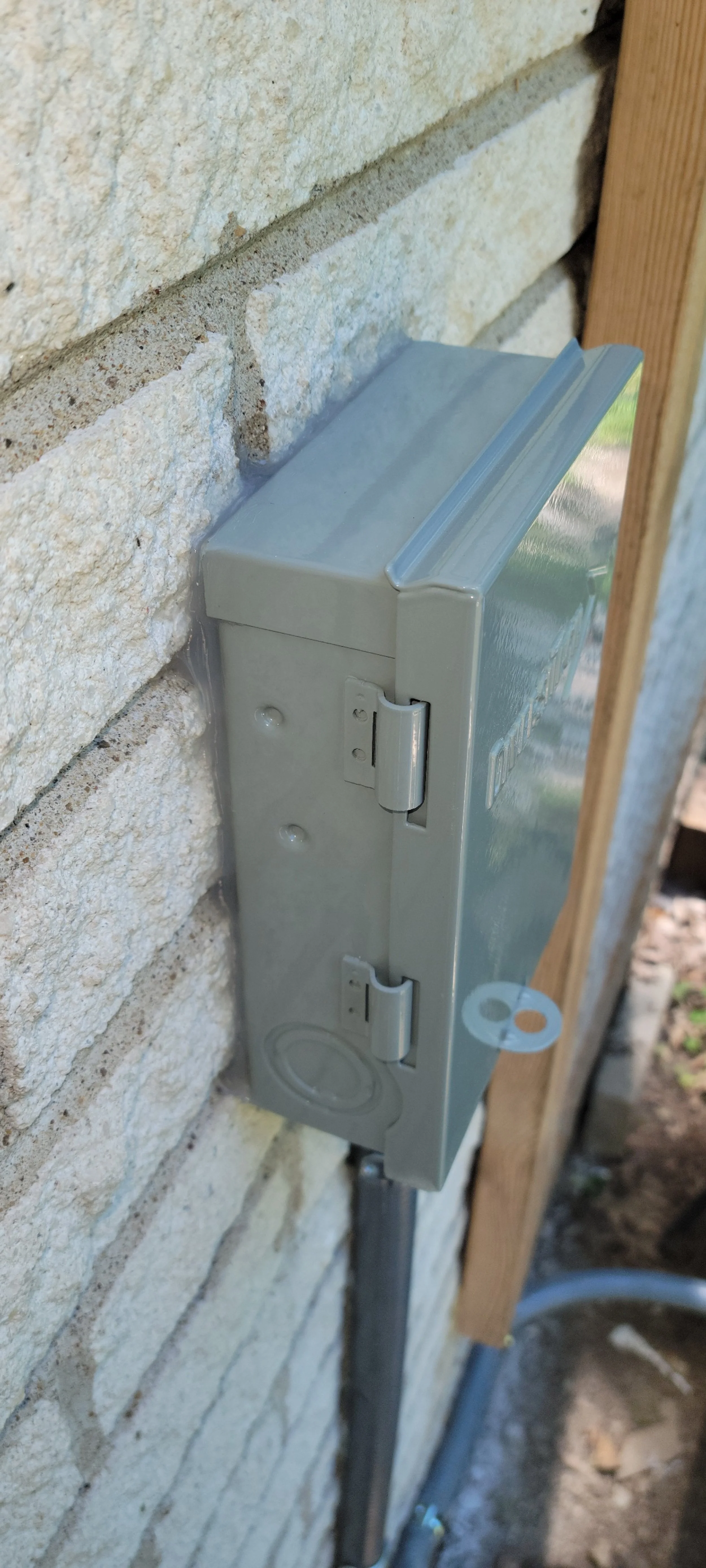 Electrical meter box mounted on a brick wall.