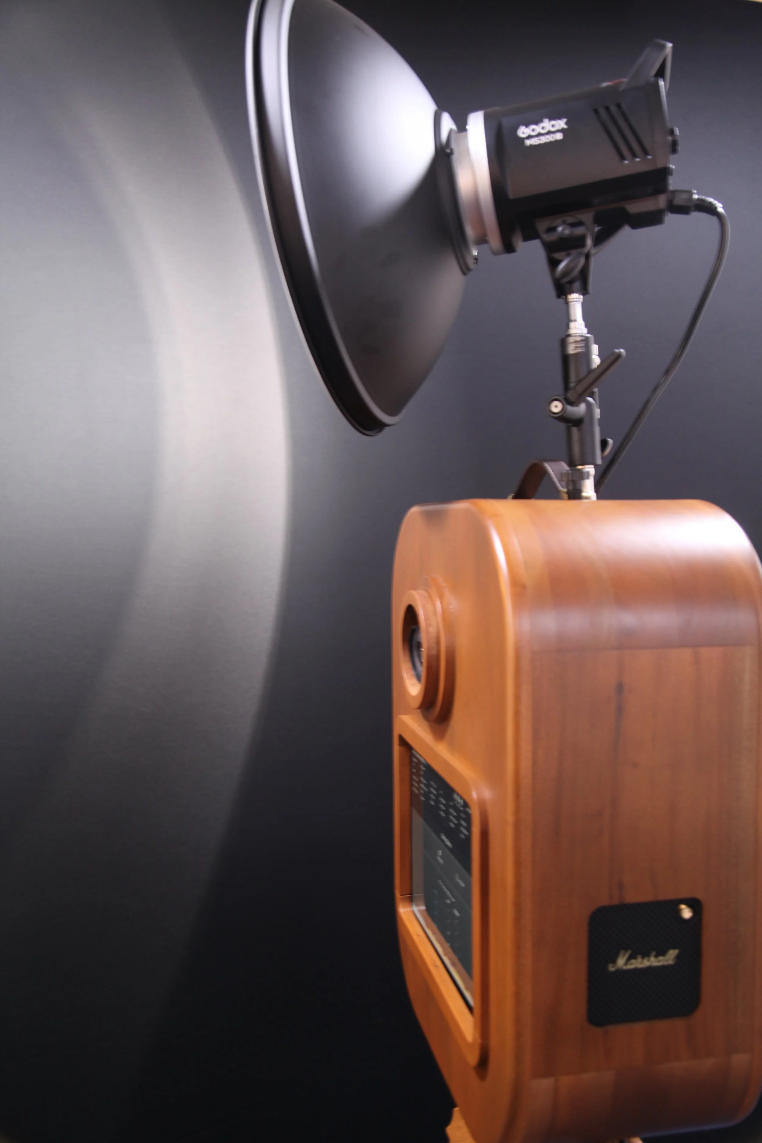 A vintage-style wooden Marshall speaker with a control panel and a round speaker opening.