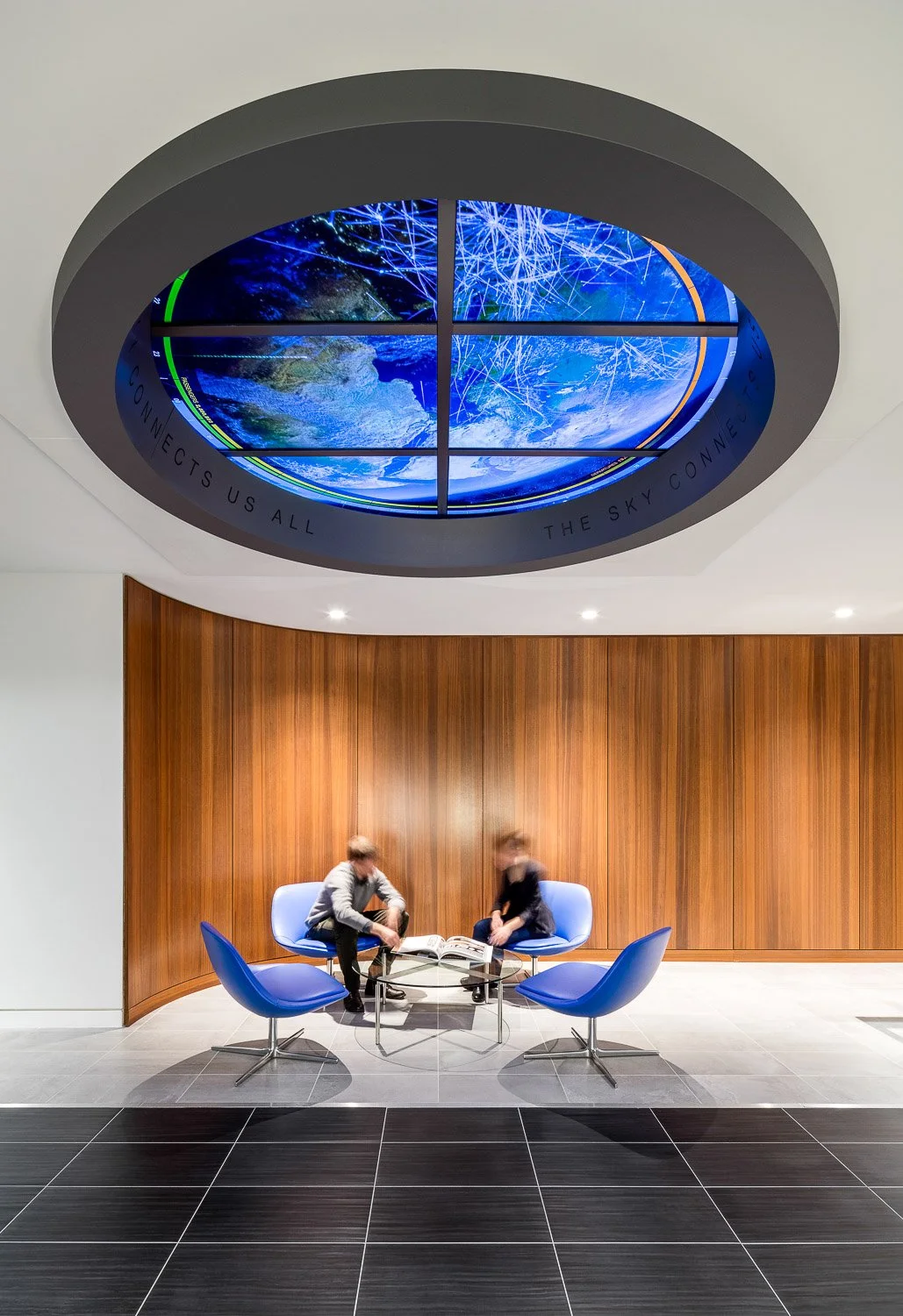 Upon arrival, a dynamic digital oculus overhead offers a bird's eye view of the earth with simulated flight paths and data points.
