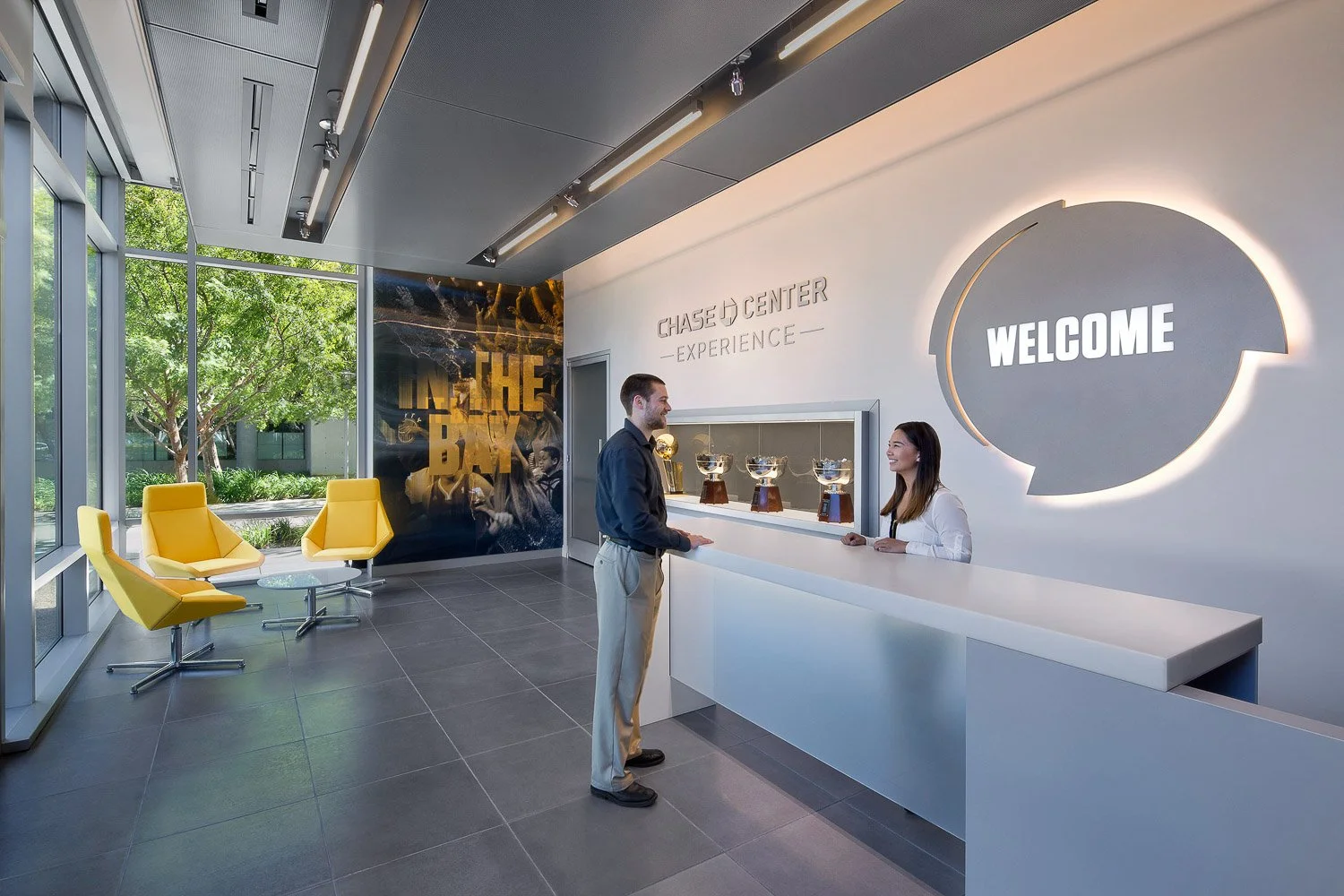 Arrival: Visitors are welcomed by VIP hospitality, customized welcome screen, and championship trophy case where they meet their host.