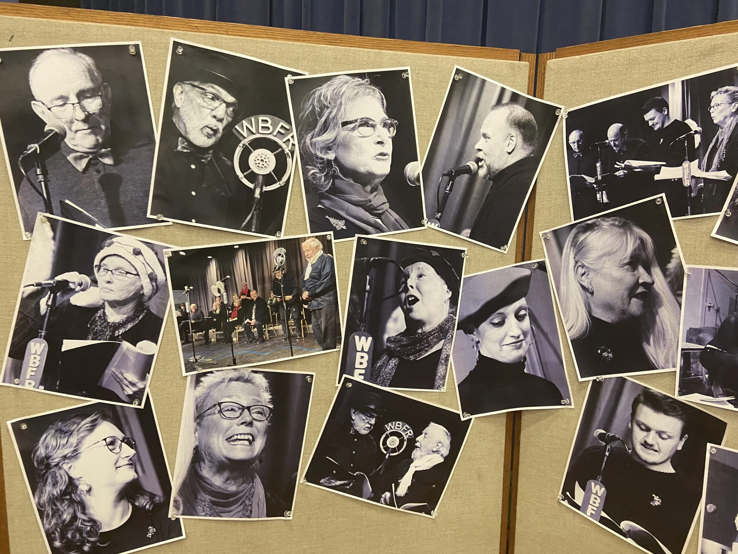 Black and white photos of various people, some speaking into microphones, displayed on a beige bulletin board.