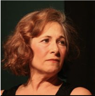 A woman with wavy, shoulder-length auburn hair looking to her right with a serious expression.