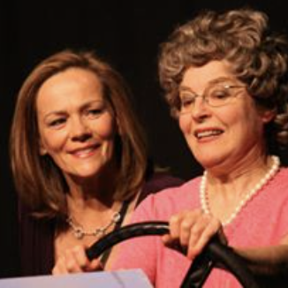 Two women, one older and one middle-aged, smiling and holding a black cane.