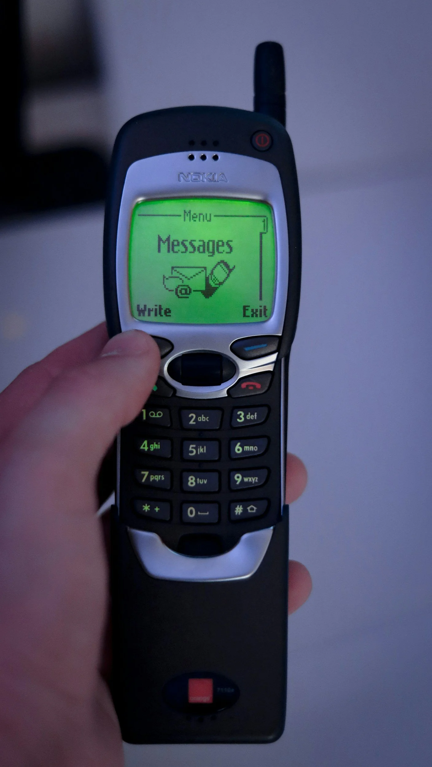 An older model Nokia cell phone displaying a message menu on a green screen with options for 'Write' and 'Exit'.