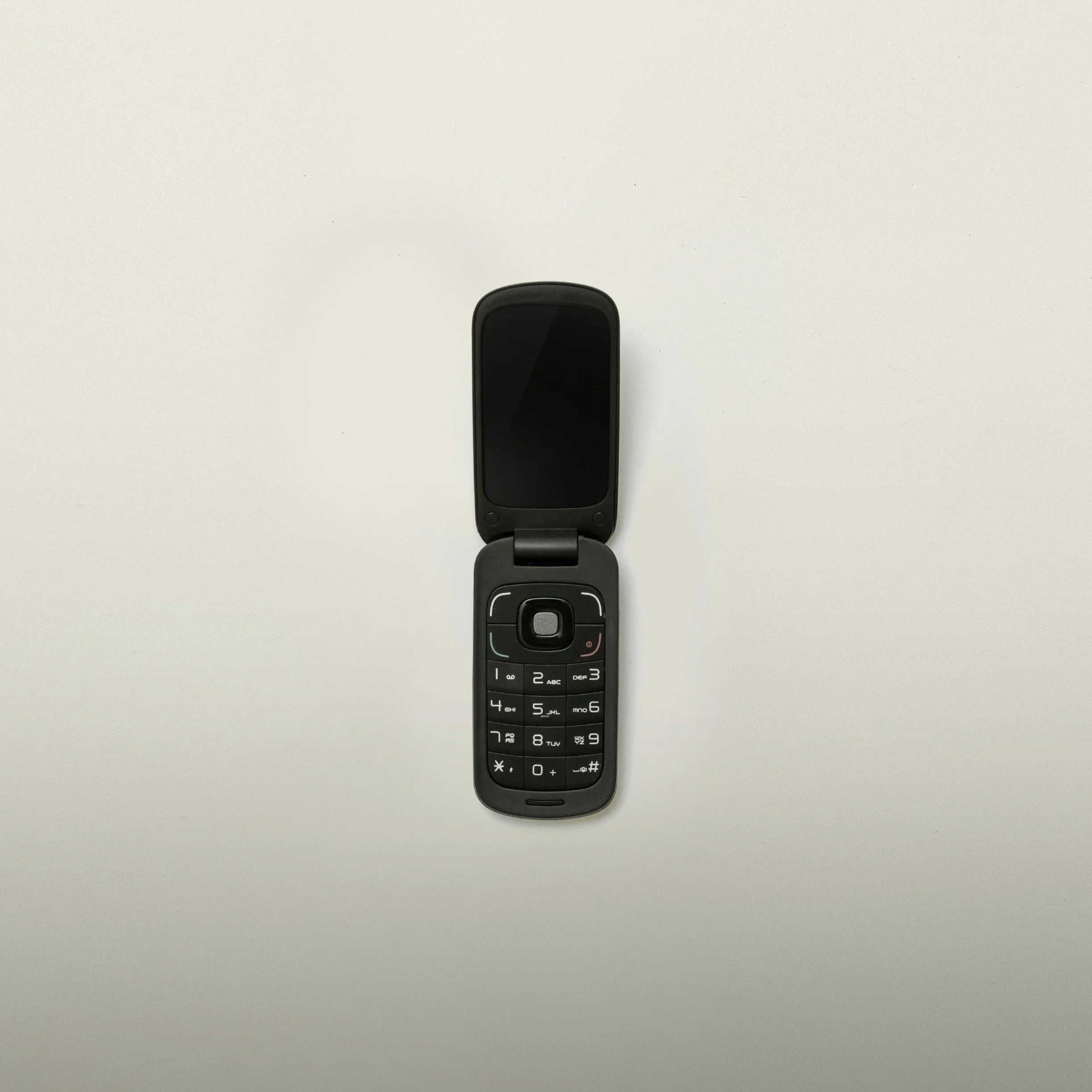 A black flip phone with an open flip, displaying keypad and screen, placed on a plain light-colored background.
