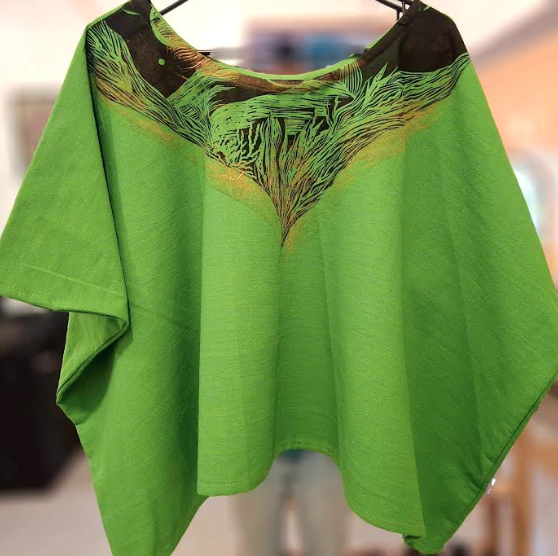 Pañuelo o bufanda de color verde con diseño de ramas en negro en la parte superior.