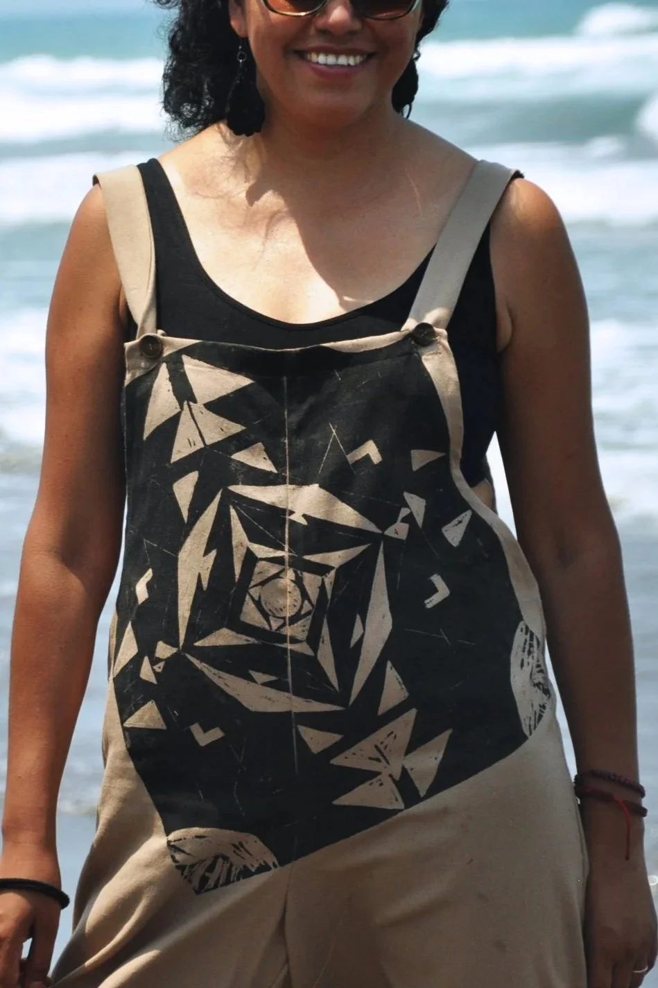 Mujer con vestido sin mangas negro con diseño abstracto en la playa
