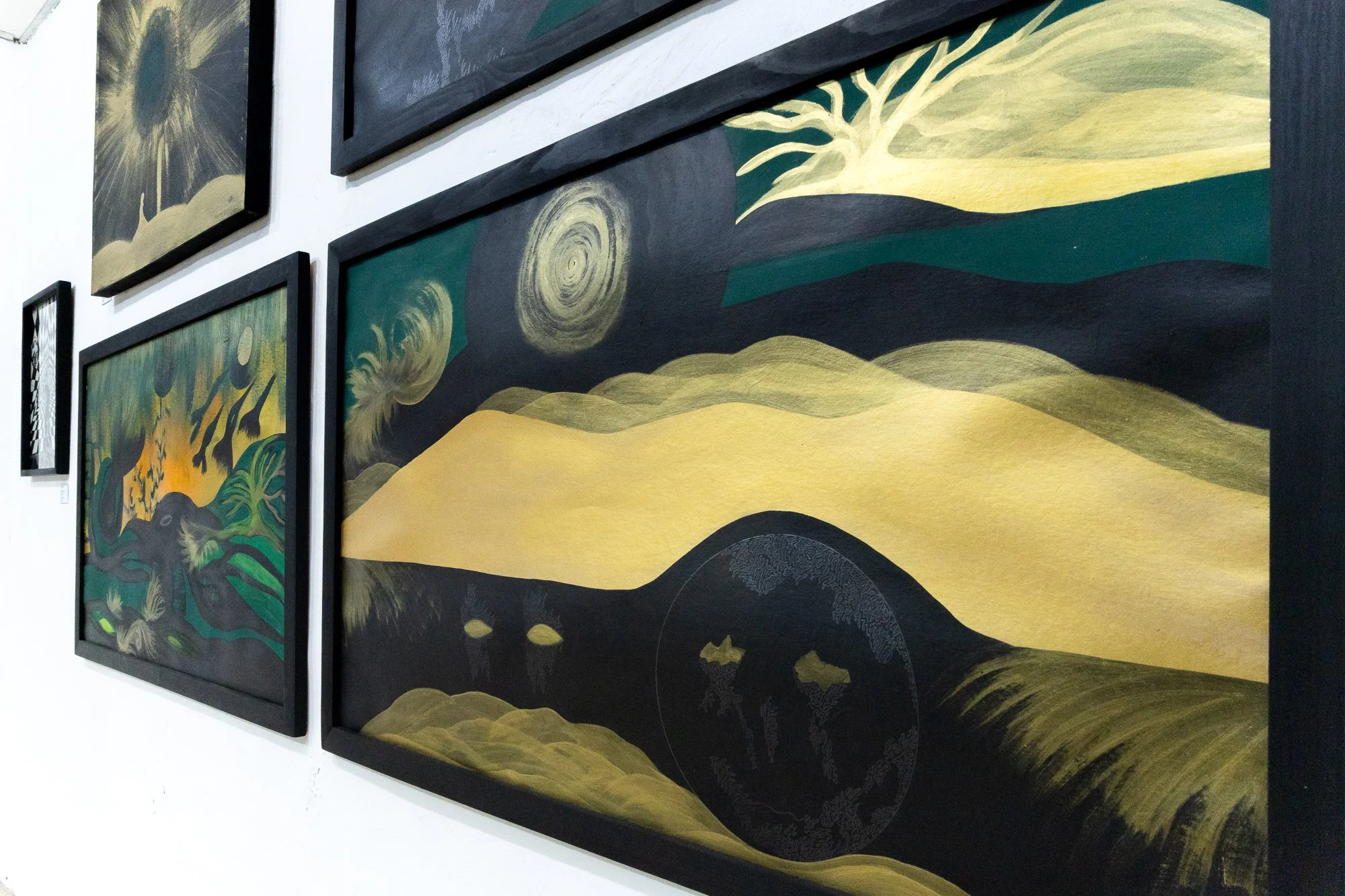 Cuadros en una galería que muestran obras con estilos similares a 'La noche estrellada' y 'El sembrador', usando tonos verdes, dorados y negros.