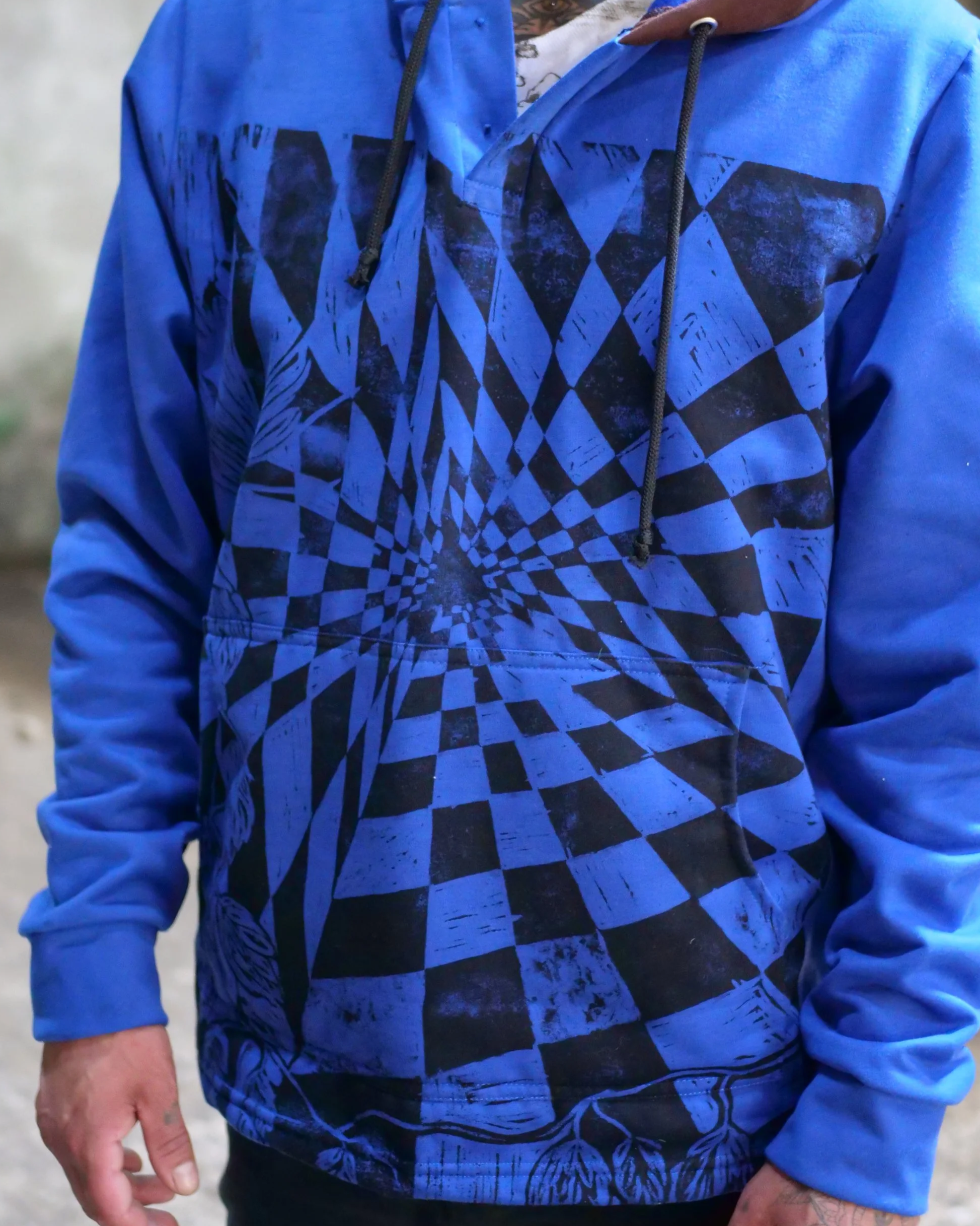 Persona con sudadera azul con un patrón de ilusión óptica en espiral en tonos negros y azules