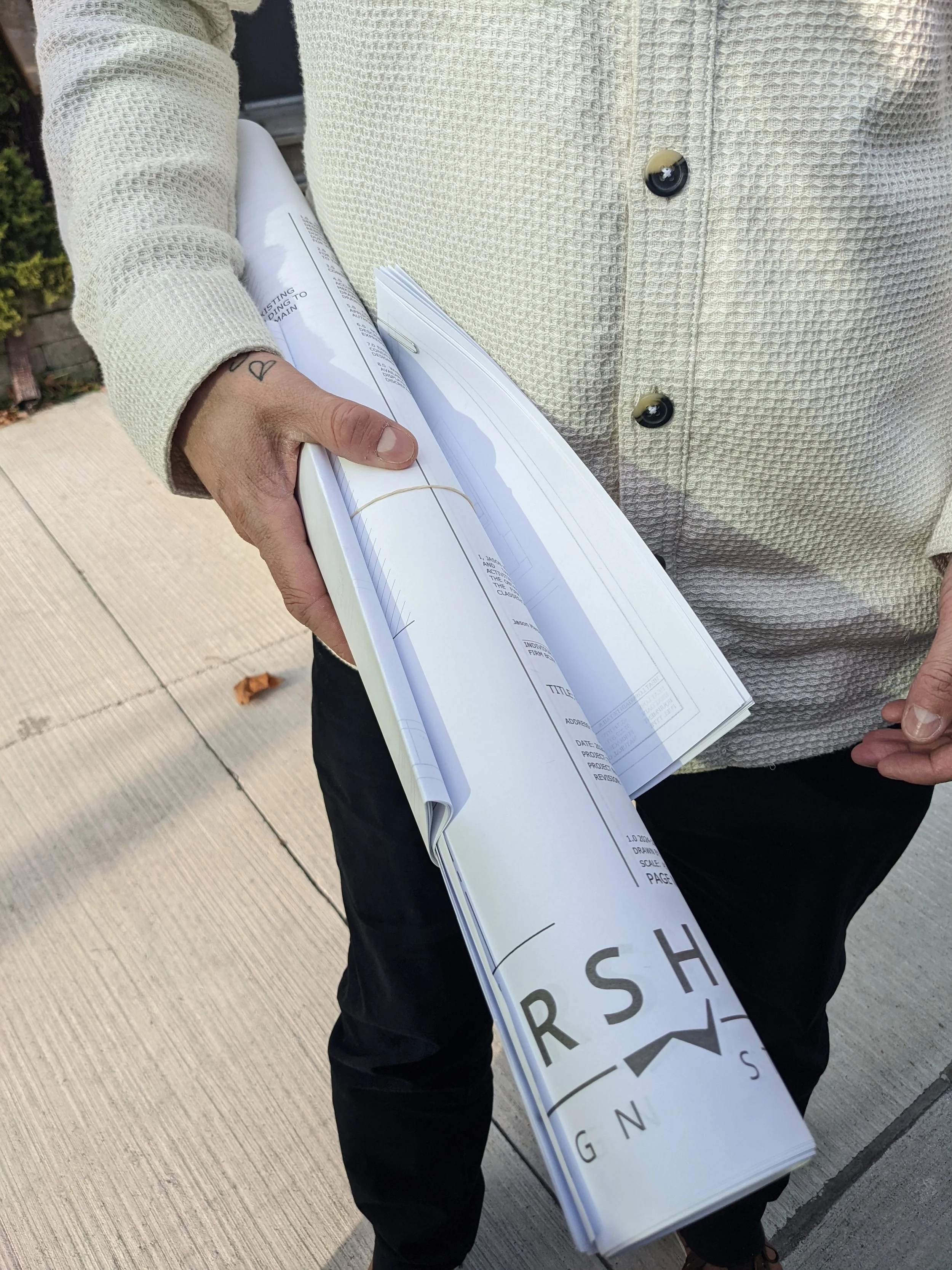Person holding rolled-up blueprints or architectural plans for building permit submission to local municipalities