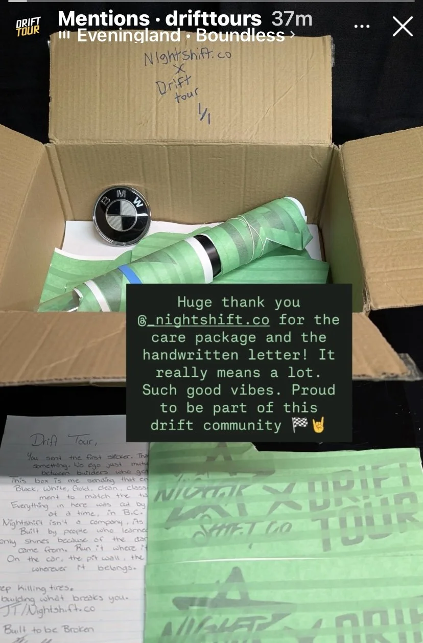 Open cardboard box containing a BMW logo, a handwritten letter, and green wrapping paper with a Nightshift.co sticker, with notes and messages about a drift tour community.