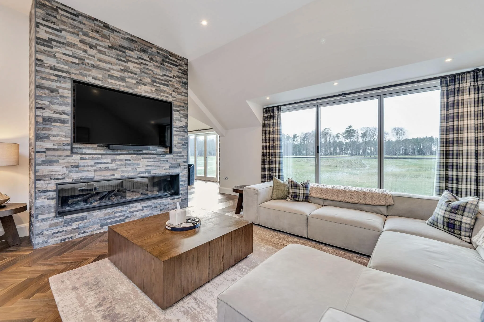 High-end living room with feature stone fireplace and large windows overlooking golf course.