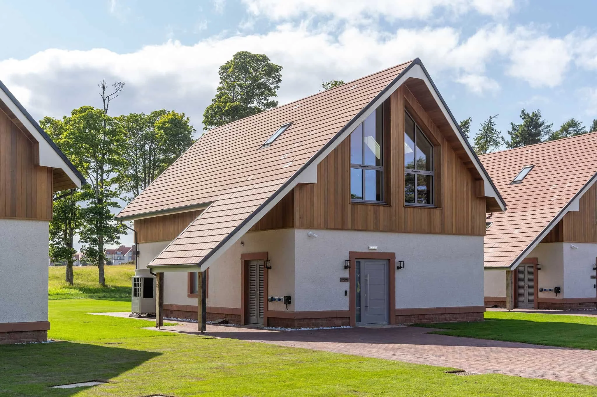 Contemporary timber-clad holiday cabin with pitched roof in landscaped setting.